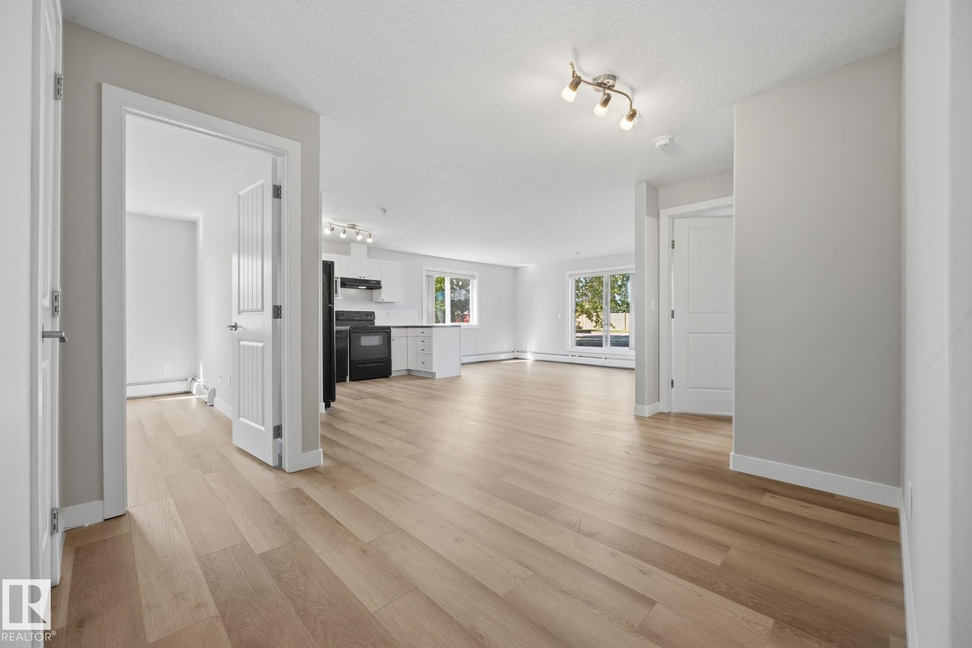 Wood-finish flooring throughout, white walls, and track lighting - #122 240 Spruce Ridge Rd, Spruce Grove, AB