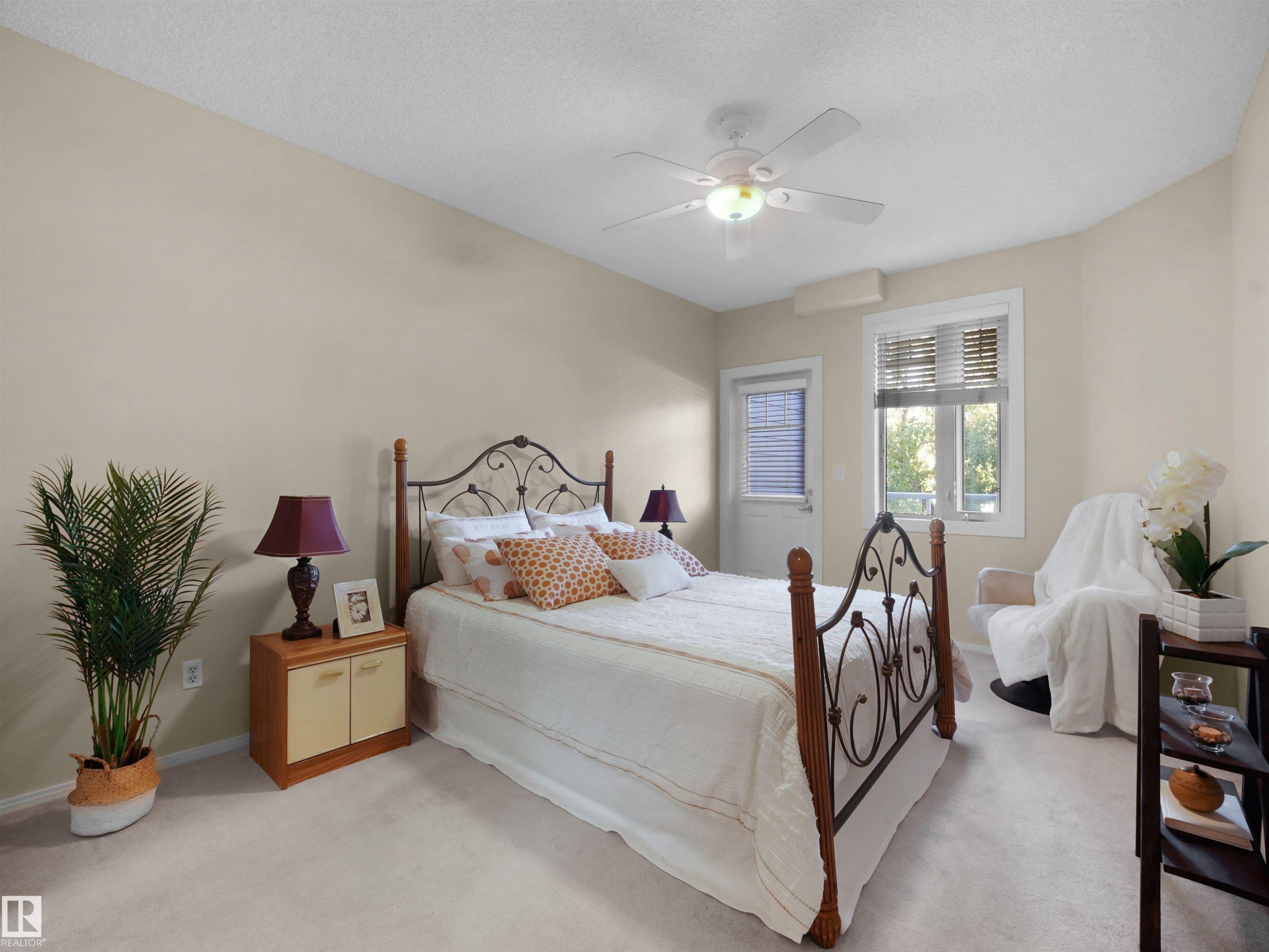 Light-colored wall paint, white ceiling fan, wood-finish nightstand, white window blinds, and white door - #206 12111 51 Av Nw, Edmonton, AB