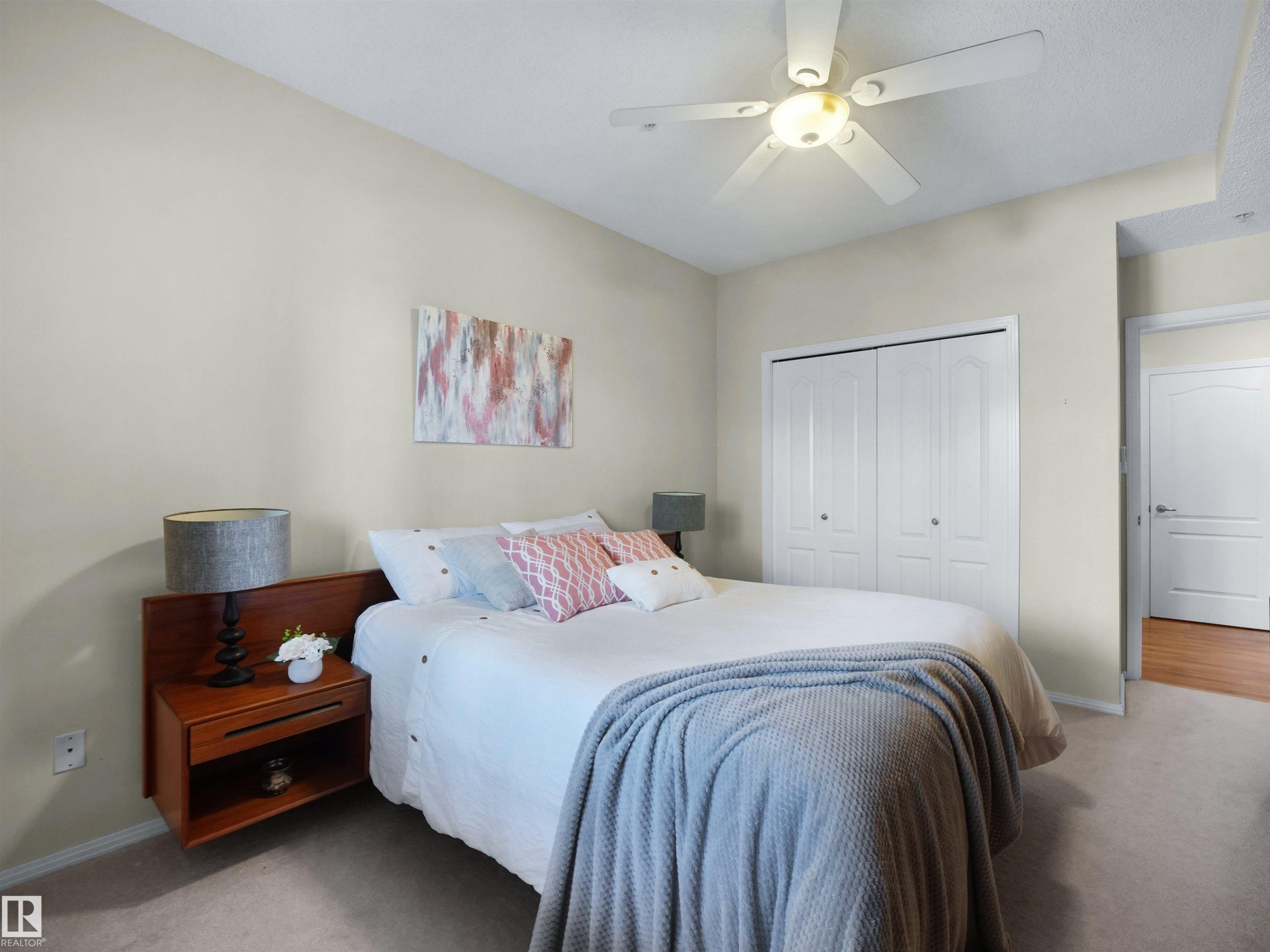 Vaulted ceiling, ceiling fan with integrated lighting, bi-fold closet doors, wall-to-wall carpeting, and an interior door with panel detailing - #206 12111 51 Av Nw, Edmonton, AB