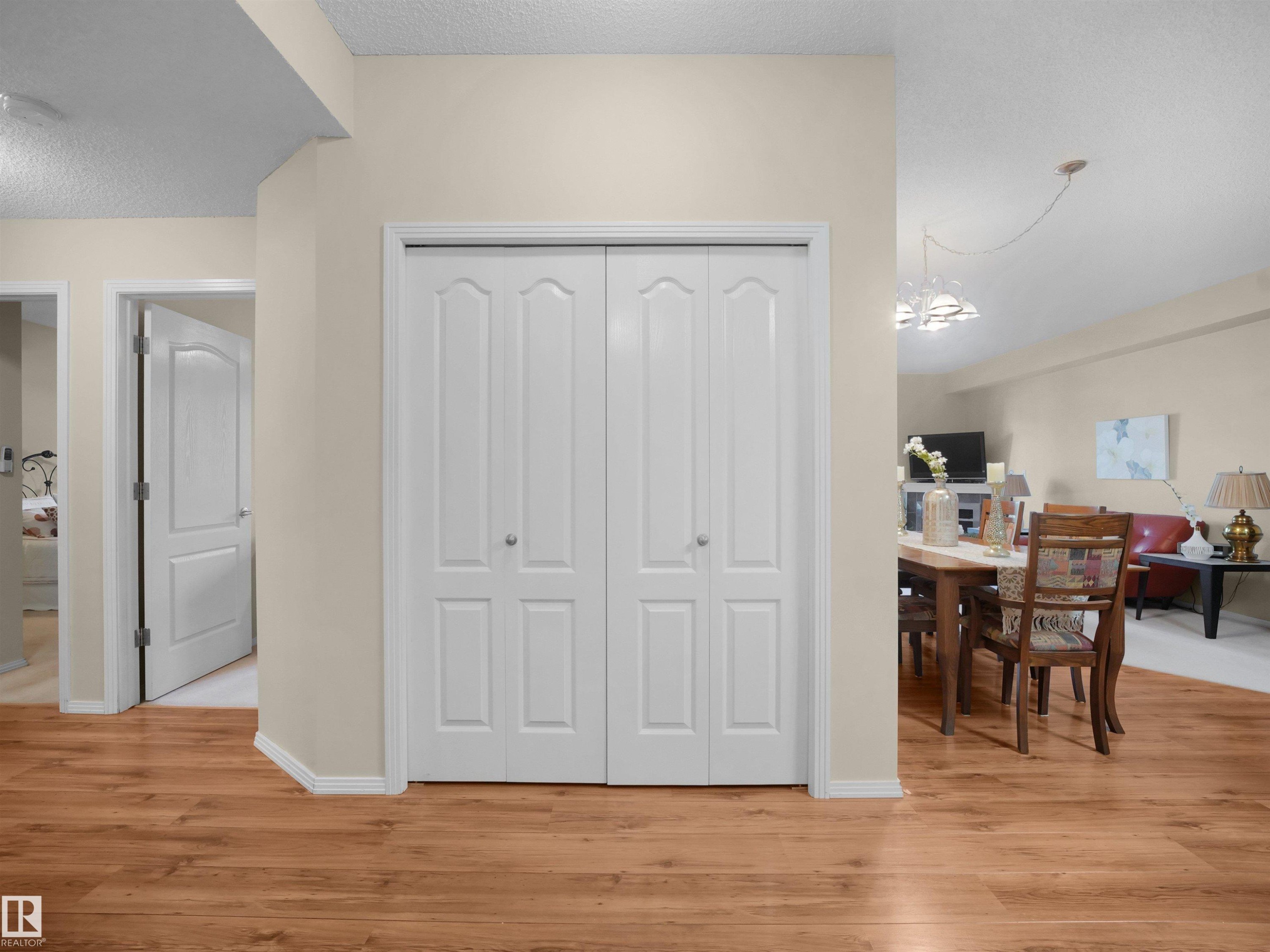 Wood-finish flooring throughout, white trim, and bi-fold closet doors - #206 12111 51 Av Nw, Edmonton, AB
