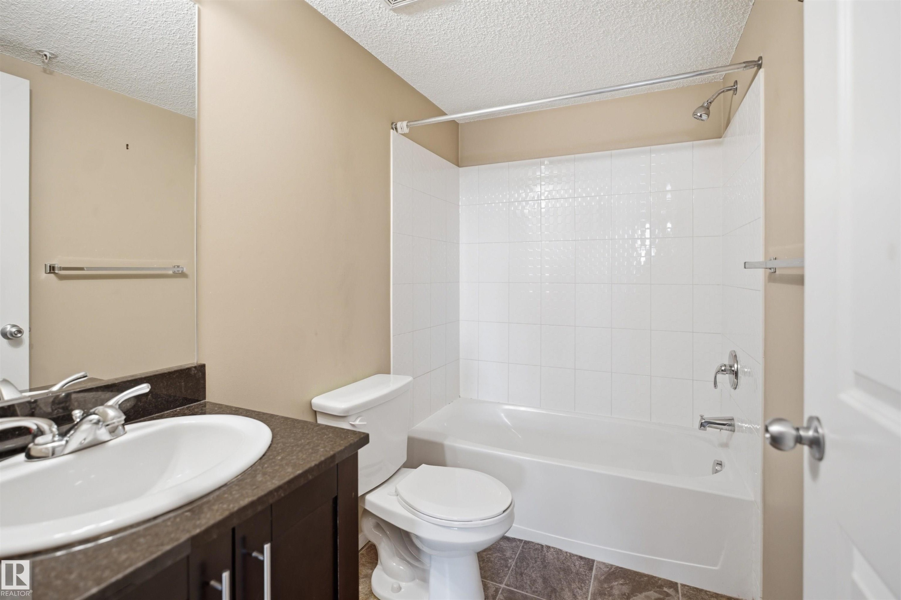 Bathroom featuring a built-in vanity with a dark countertop, white oval sink, and a chrome faucet - #225 1510 Watt Dr Sw, Edmonton, AB