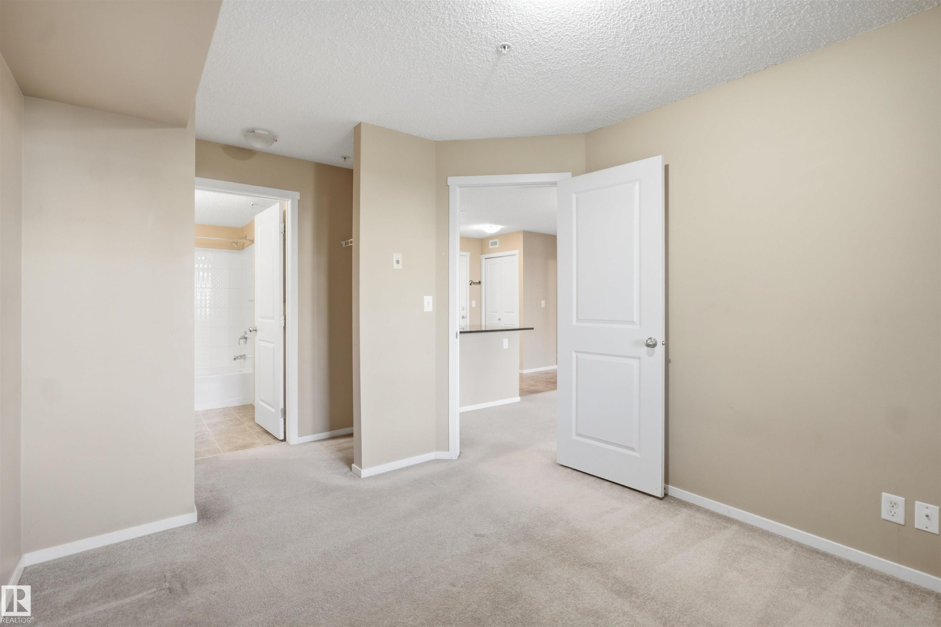 Neutral paint palette, textured ceiling, light-toned carpeting, and white panel doors - #225 1510 Watt Dr Sw, Edmonton, AB