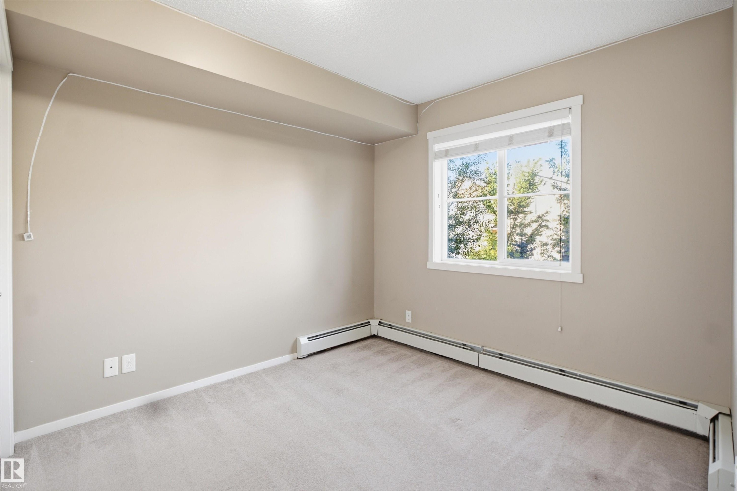 Carpeted flooring with neutral wall tones and a window with white trim - #225 1510 Watt Dr Sw, Edmonton, AB