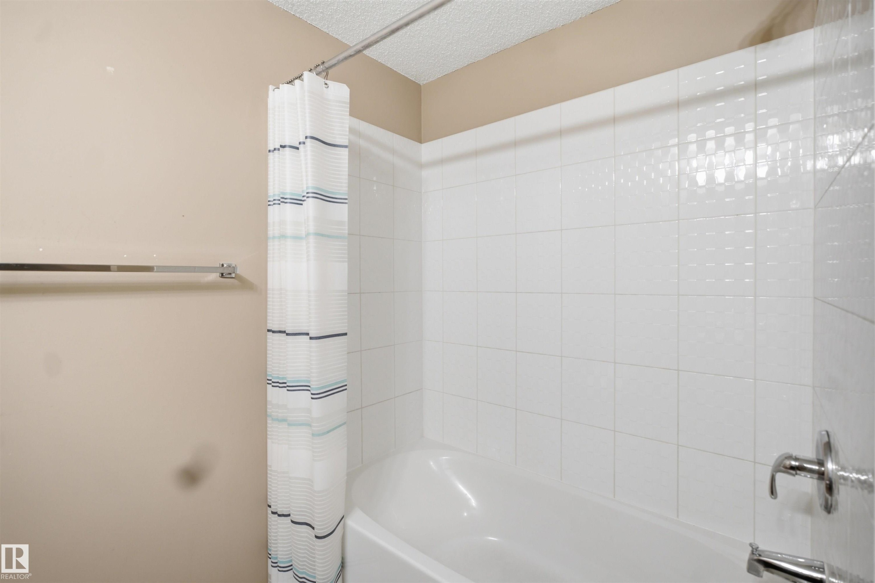 Bathtub with white tile surround and chrome fixtures - #225 1510 Watt Dr Sw, Edmonton, AB