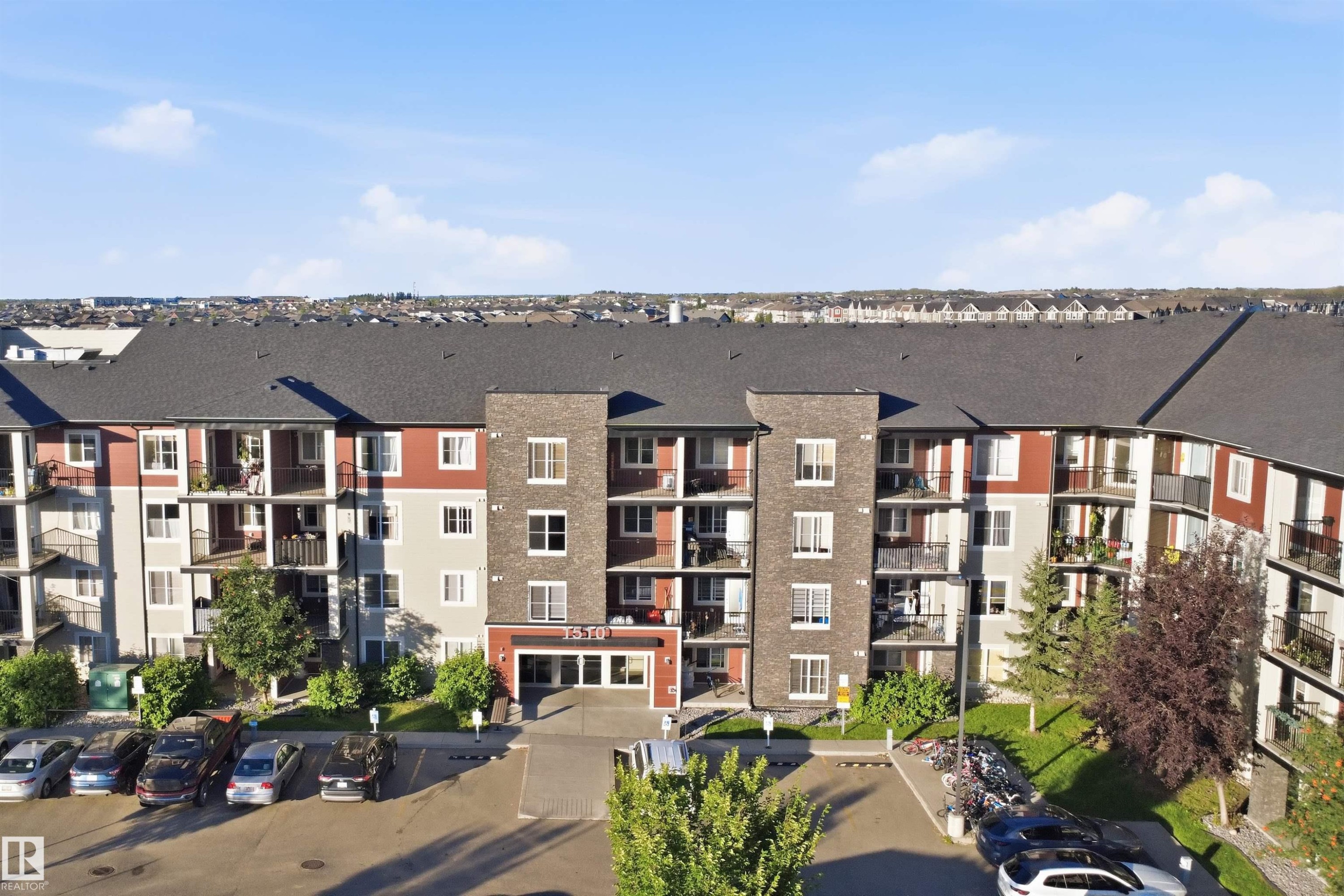 Multi-story residential building with brick and siding facade, private balconies, and an onsite parking area - #225 1510 Watt Dr Sw, Edmonton, AB