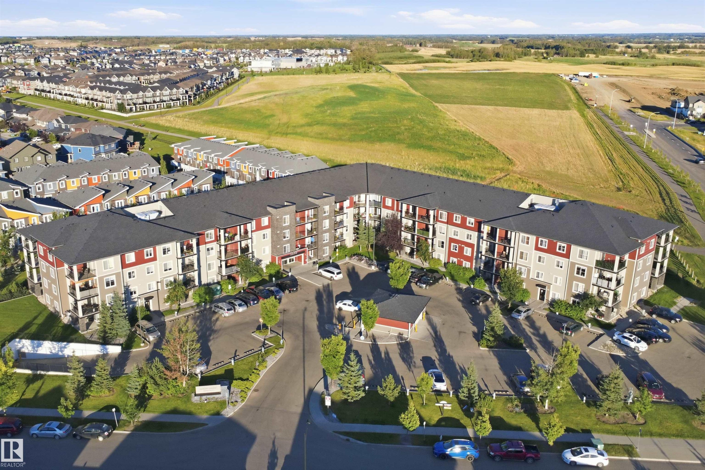 Multi-story residential building featuring balconies, ample surface parking, and perimeter landscaping - #225 1510 Watt Dr Sw, Edmonton, AB