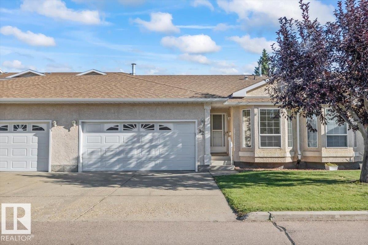 Stucco exterior with a peaked roof, two-car garage, and bay windows - #92 13320 124 St Nw, Edmonton, AB