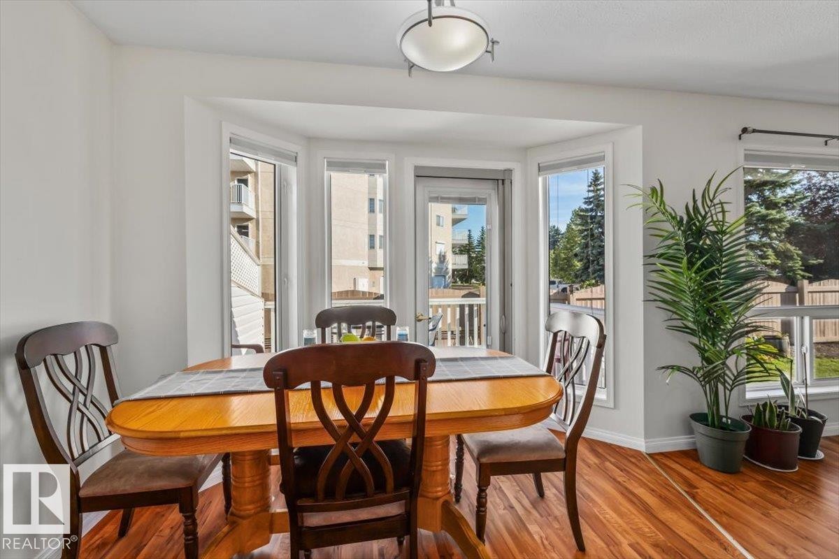 Bay window dining area with natural light, wood-finish flooring, and a glass-paneled door - #92 13320 124 St Nw, Edmonton, AB