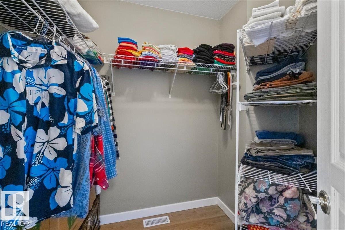 Walk-in closet featuring wire shelving, hanging rods, and wood-finish flooring - #92 13320 124 St Nw, Edmonton, AB