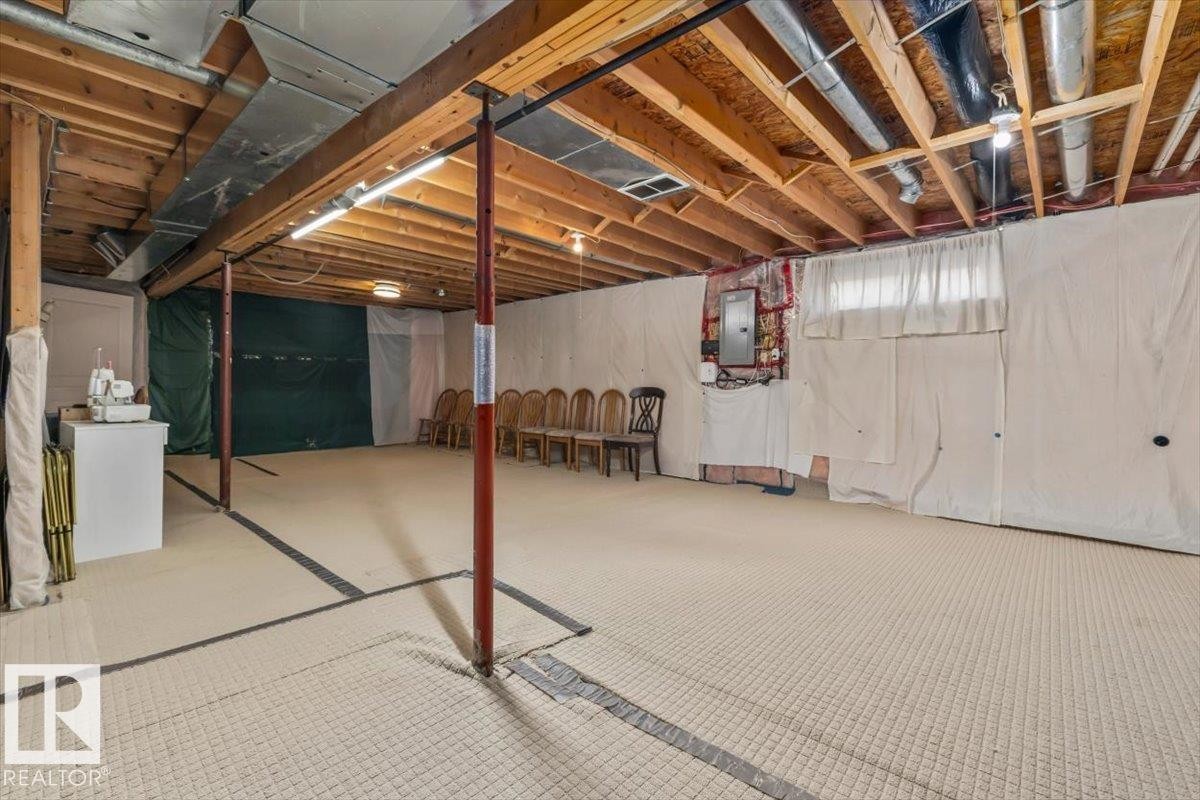 Unfinished basement space featuring exposed wooden joists, utility piping, and a concrete floor - #92 13320 124 St Nw, Edmonton, AB