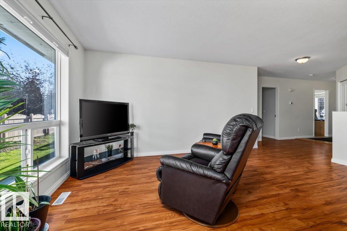 Expansive picture window, rich wood-finish flooring, recessed lighting, and a neutral wall palette - #92 13320 124 St Nw, Edmonton, AB