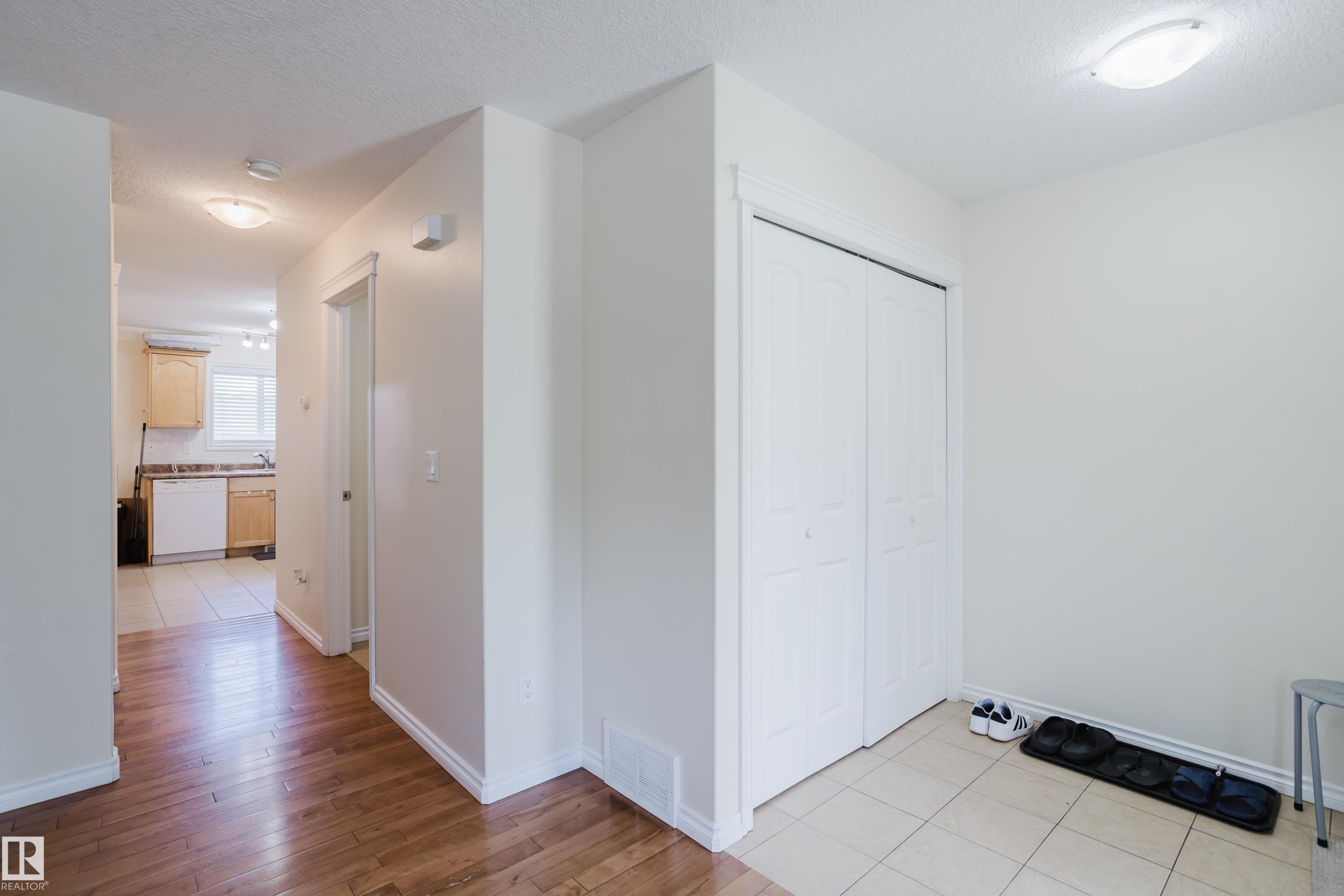 Warm wood-finish flooring, white walls, and a built-in closet with bi-fold doors - 10332 161 Street Nw, Edmonton, AB