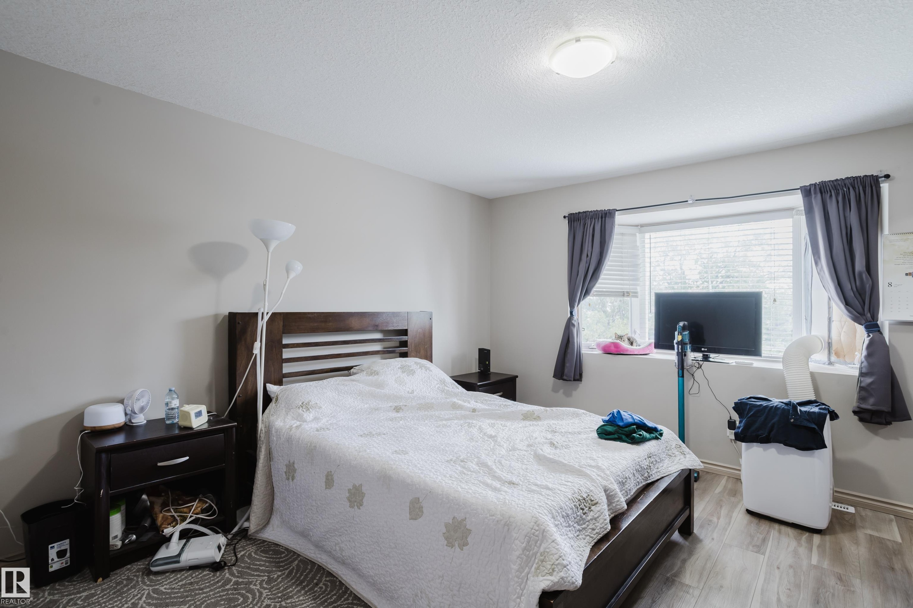 Neutral wall paint, wood-finish flooring, ceiling-mounted light fixture, window with blinds, and dark window treatments - 10334 161 Street Nw, Edmonton, AB