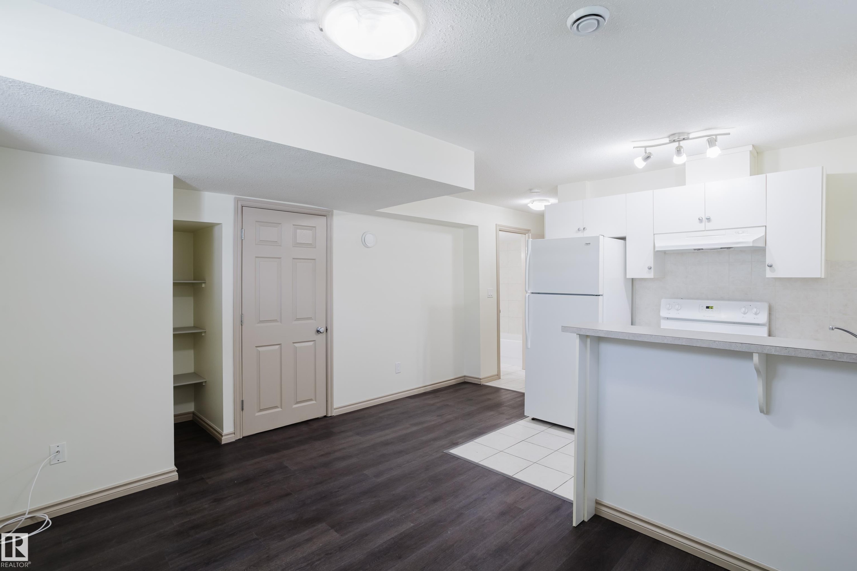 Open-concept living area with dark wood-finish flooring and built-in shelving - 10334 161 Street Nw, Edmonton, AB