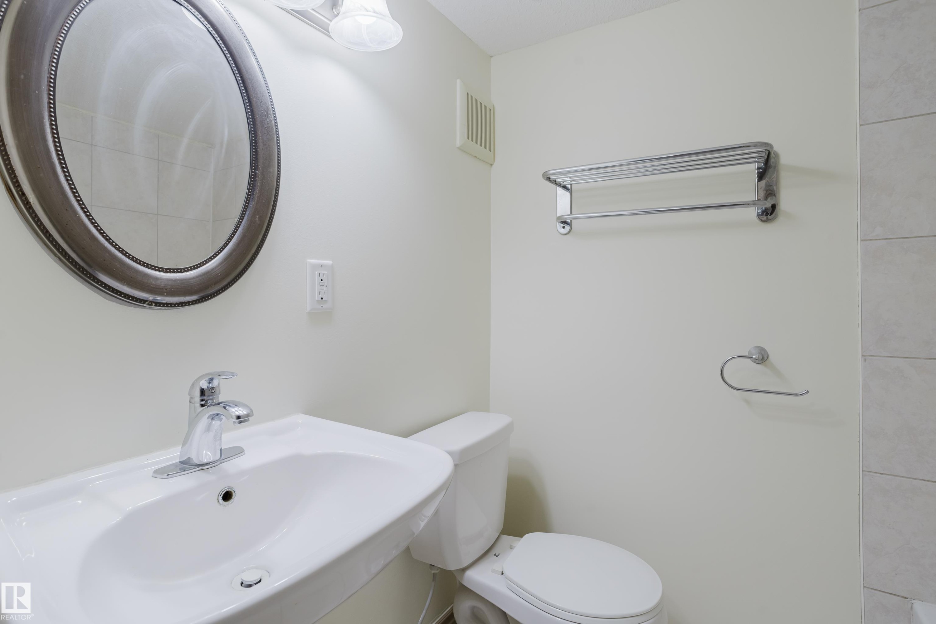 Pedestal sink with chrome faucet, oval framed mirror, and chrome towel rack - 10334 161 Street Nw, Edmonton, AB