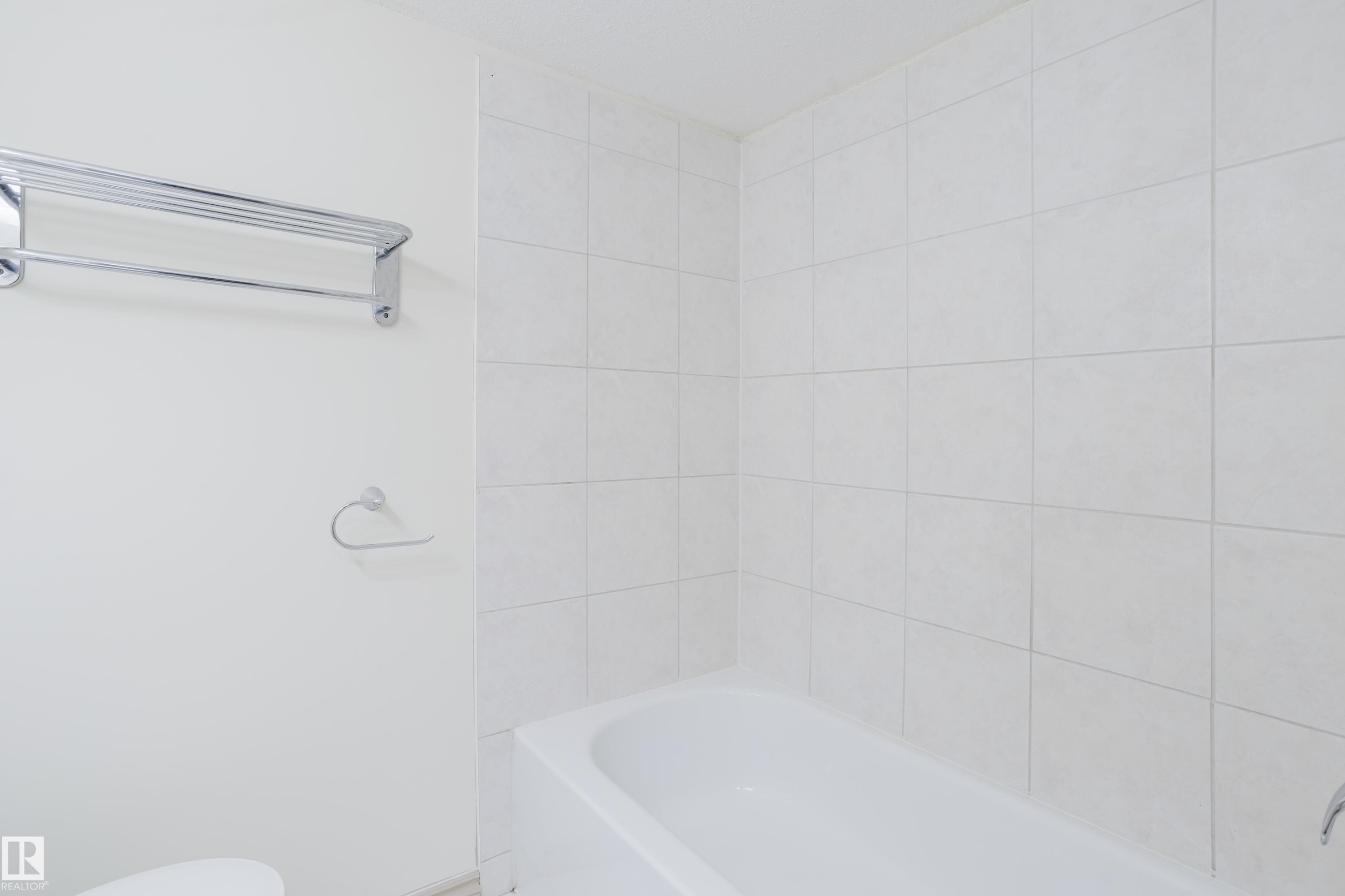 Integrated bathtub with white tile surround and chrome fixtures - 10334 161 Street Nw, Edmonton, AB