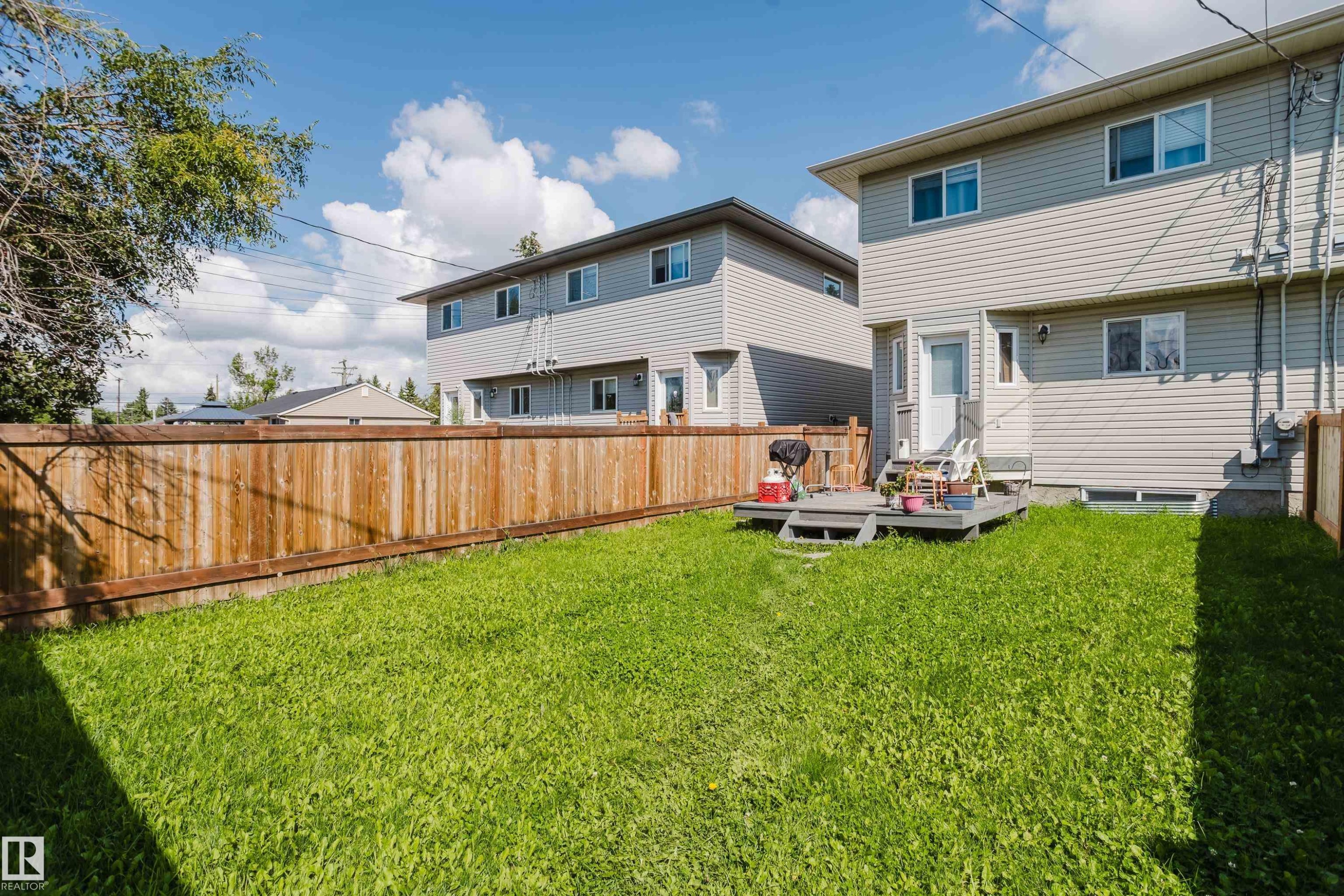 Expansive grassy yard with a wood privacy fence and a ground-level deck - 10334 161 Street Nw, Edmonton, AB