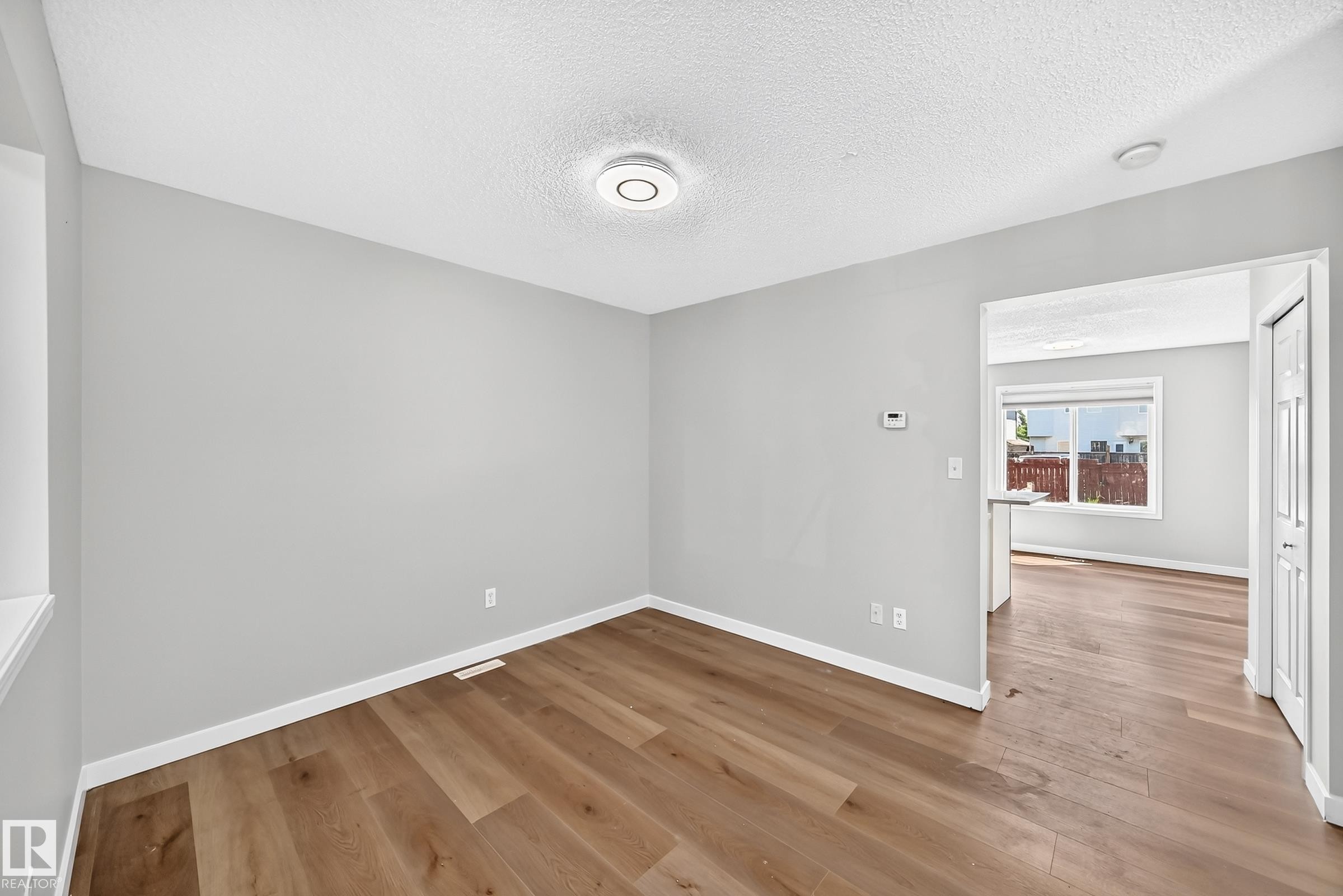 Bright room featuring wood-finish flooring, light gray walls, white trim, and a contemporary ceiling light fixture - 203 84 Street Sw, Edmonton, AB - Indoor Photo Showing Other Room