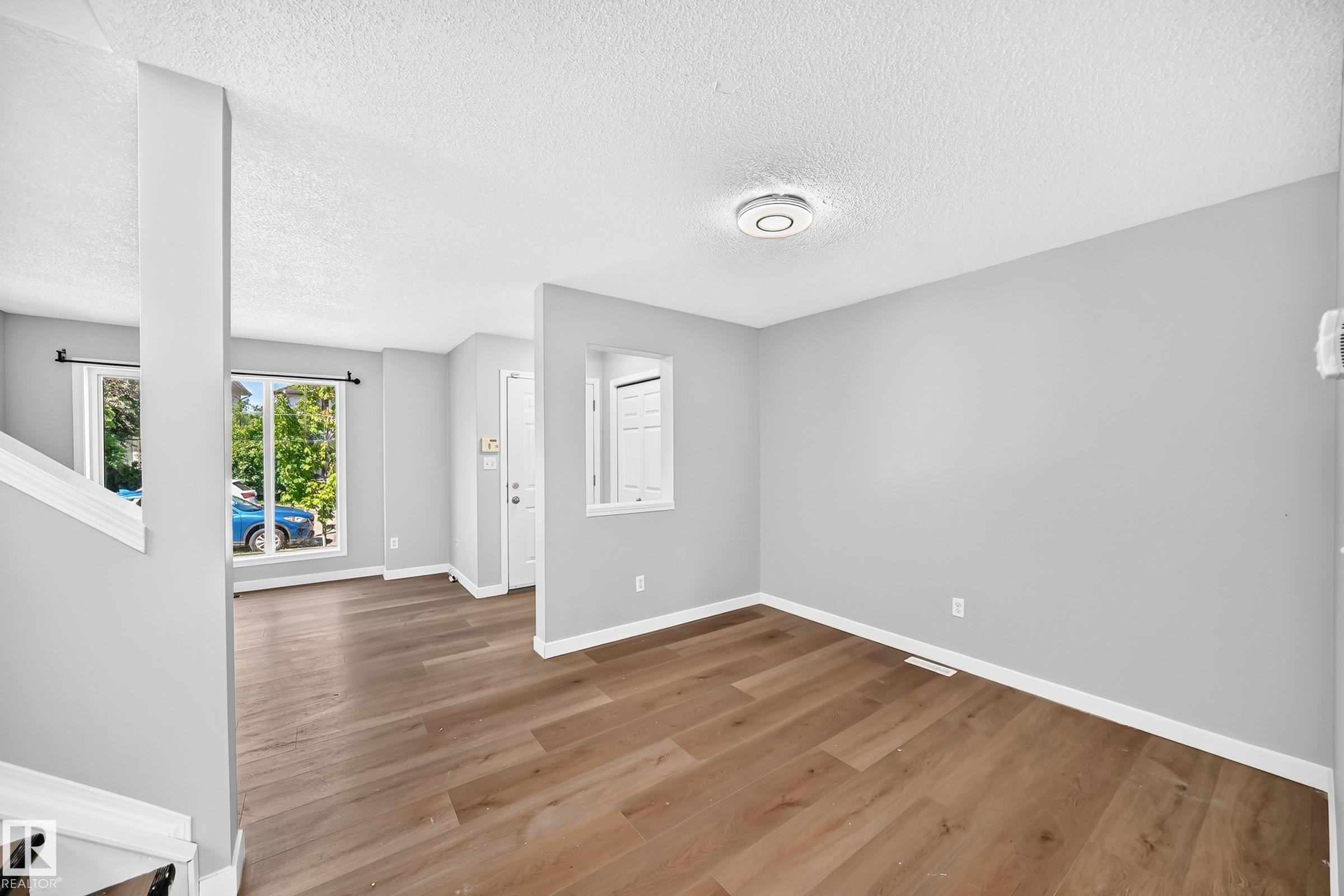 Open concept living space featuring wood-finish flooring and light gray painted walls - 203 84 Street Sw, Edmonton, AB - Indoor Photo Showing Other Room