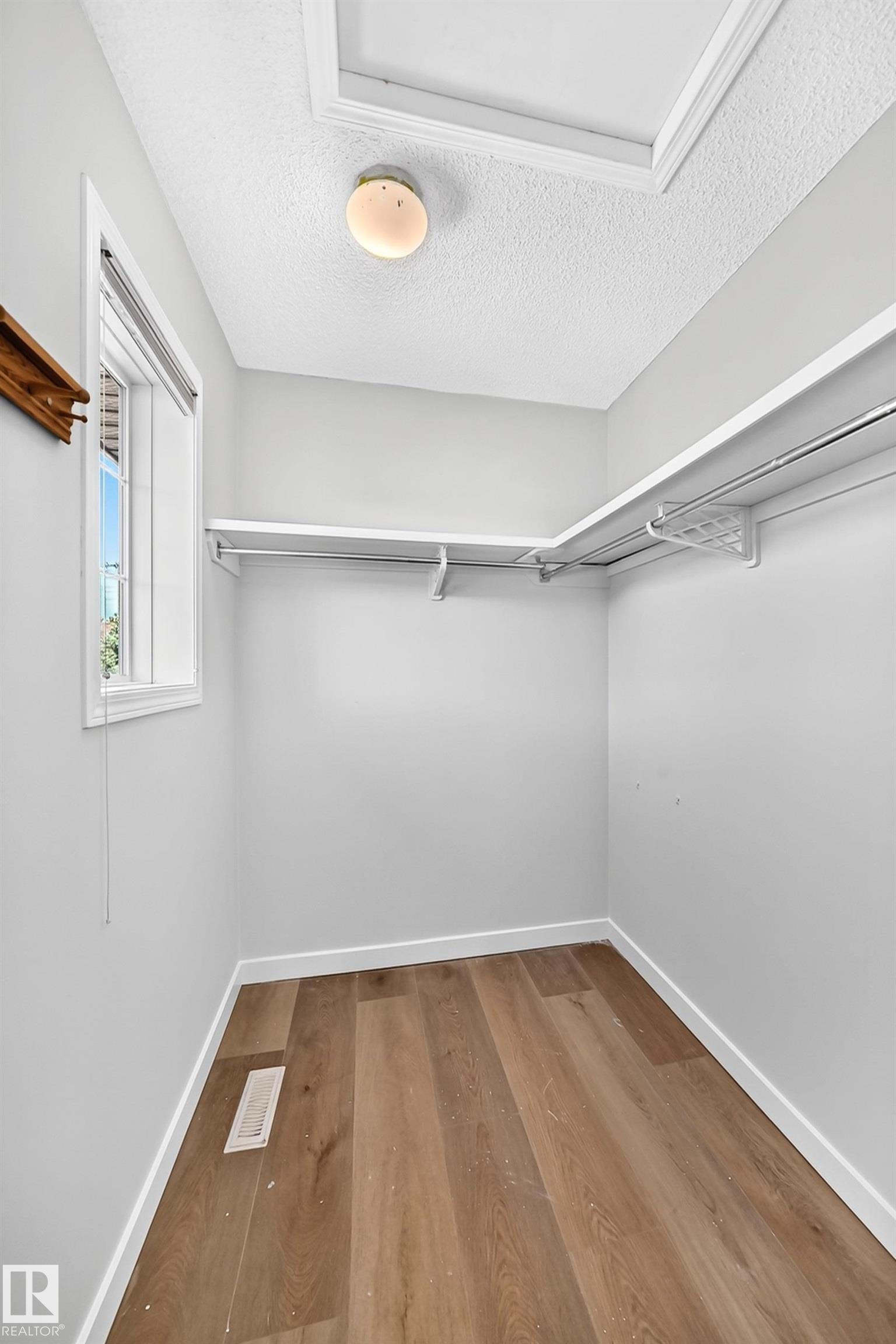 Walk-in closet with wood-finish flooring, white baseboards, and built-in shelving - 203 84 Street Sw, Edmonton, AB - Indoor With Storage