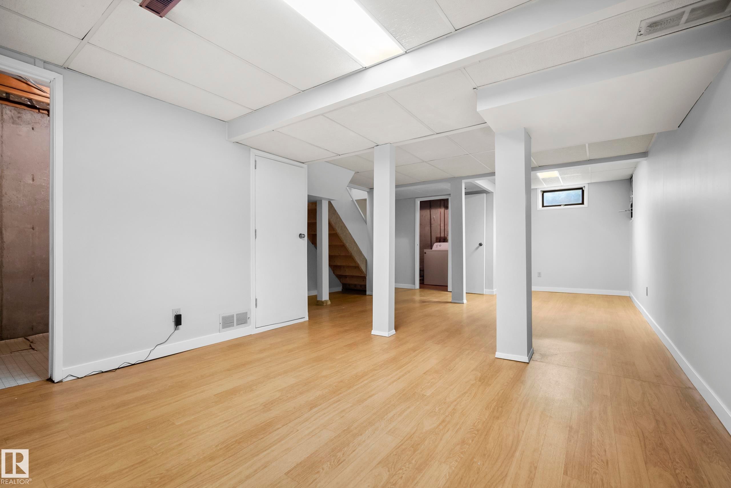 Finished lower level with light wood-finish flooring, recessed lighting, and white trim - 3173 139 Avenue Nw, Edmonton, AB