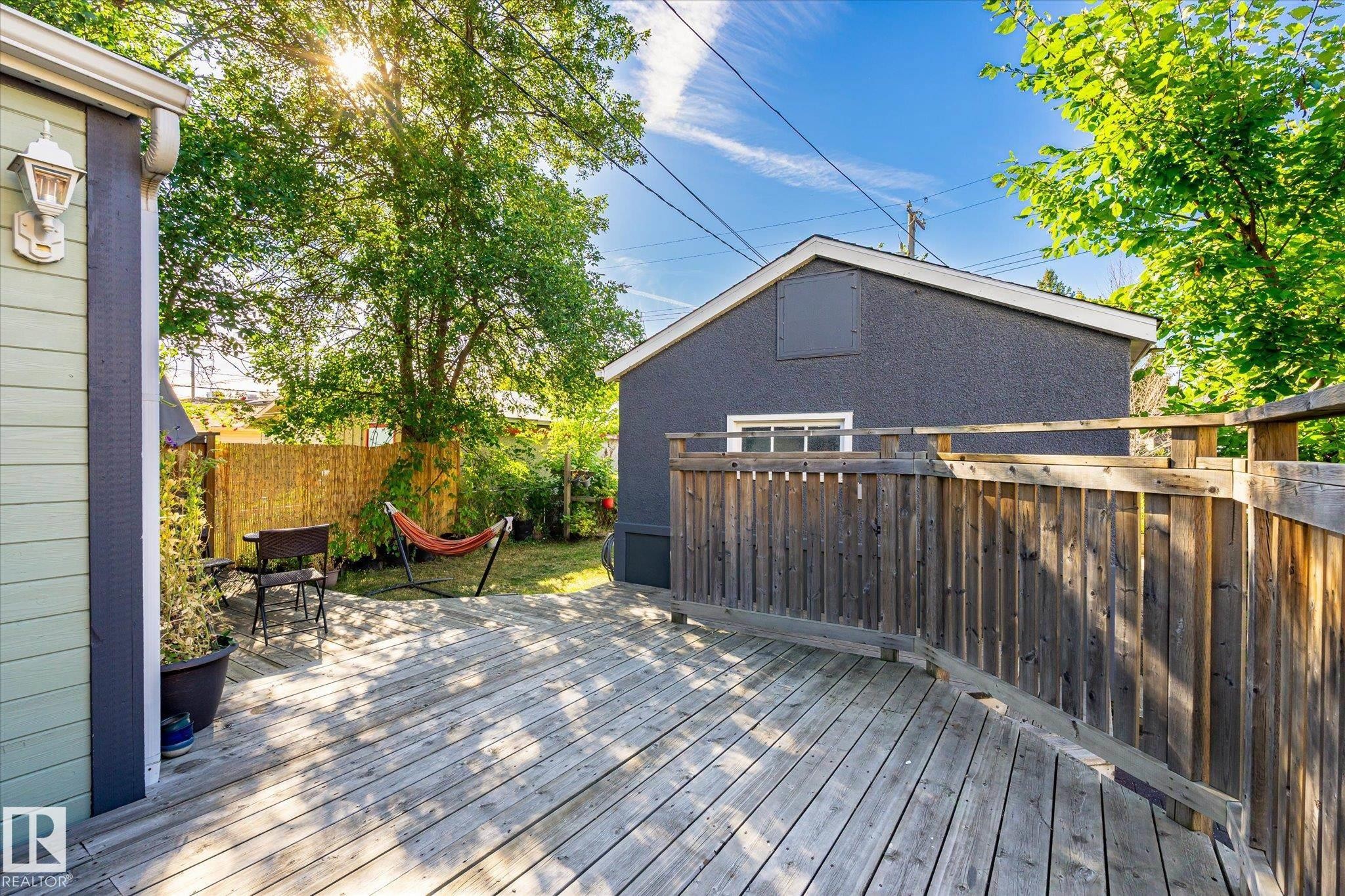 Expansive wood deck with wood privacy fencing, a separate garden structure with siding, and a rear structure with stucco finish - 10943 72 Avenue Nw, Edmonton, AB
