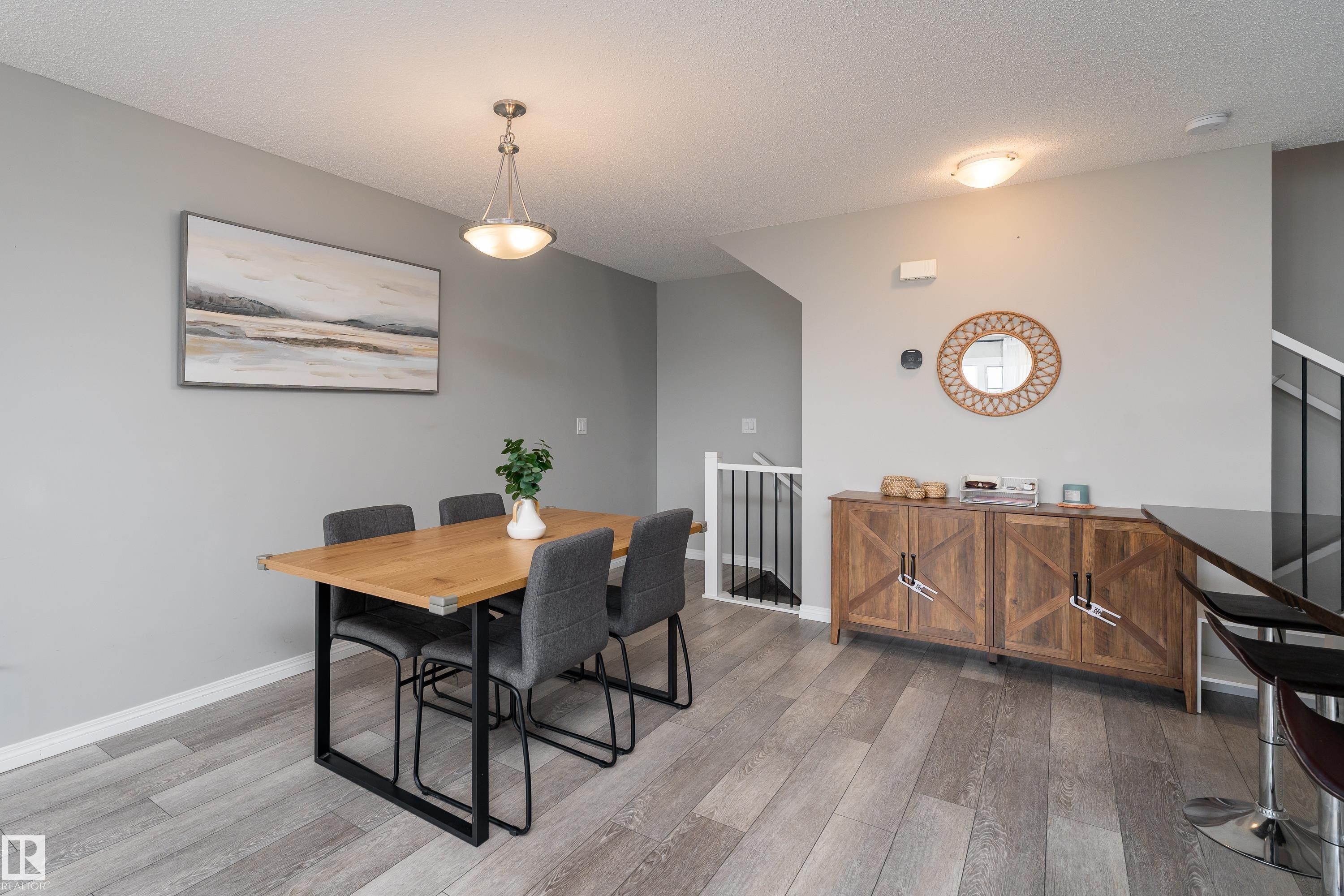 Wood-finish flooring throughout, with a built-in wood-look side cabinet - 20247 16 Avenue Nw, Edmonton, AB