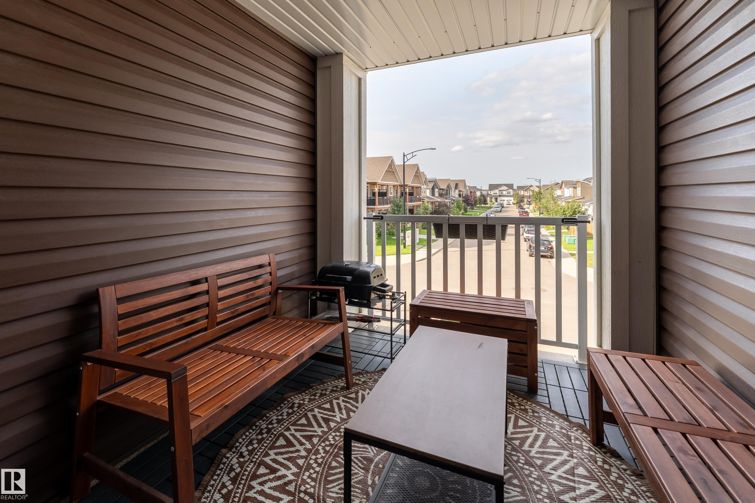 Balcony featuring horizontal siding, white railing, and a streetscape backdrop - 20247 16 Avenue Nw, Edmonton, AB