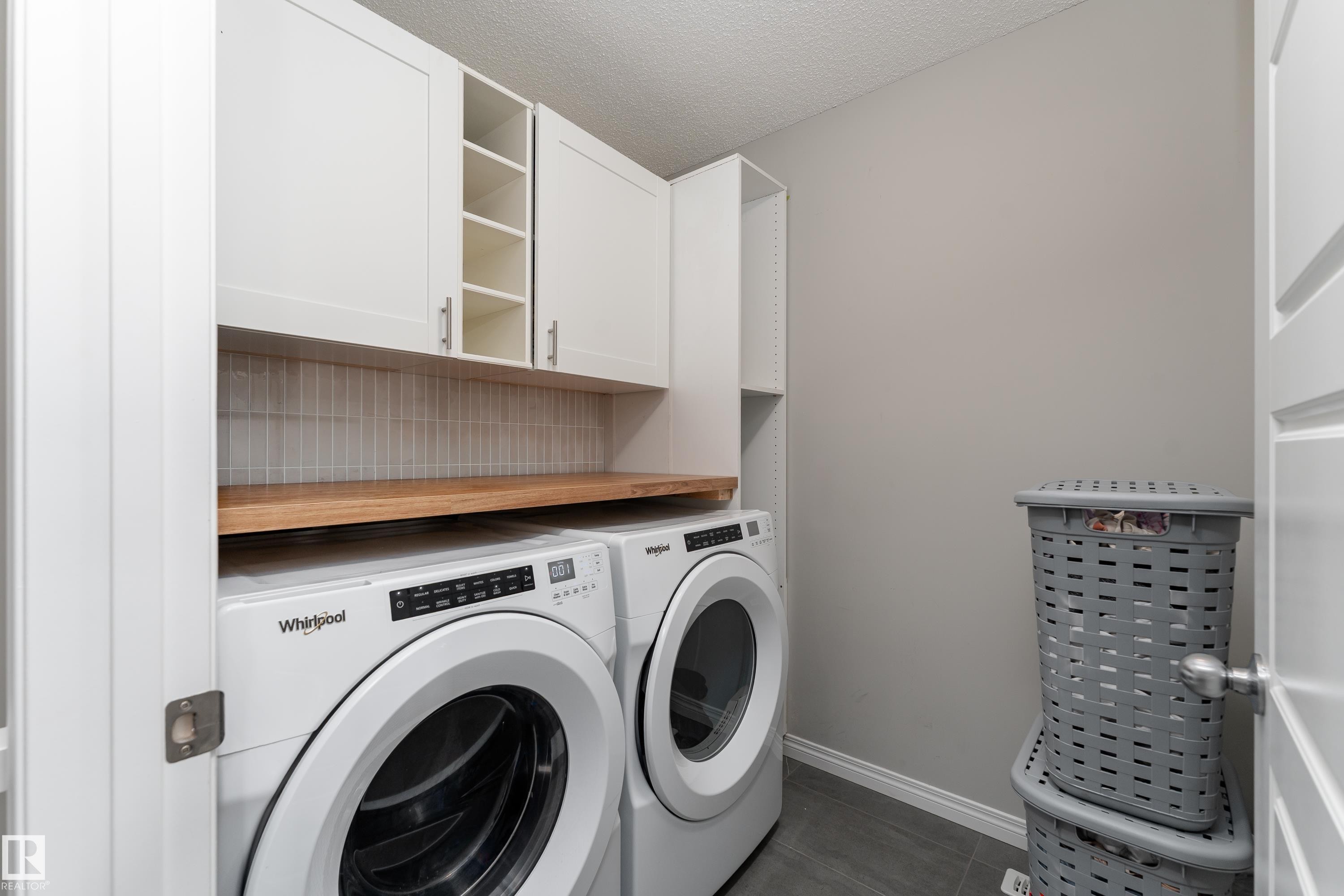 Built-in white cabinetry, open shelving, wood-finish countertop, and a tiled backsplash - 20247 16 Avenue Nw, Edmonton, AB