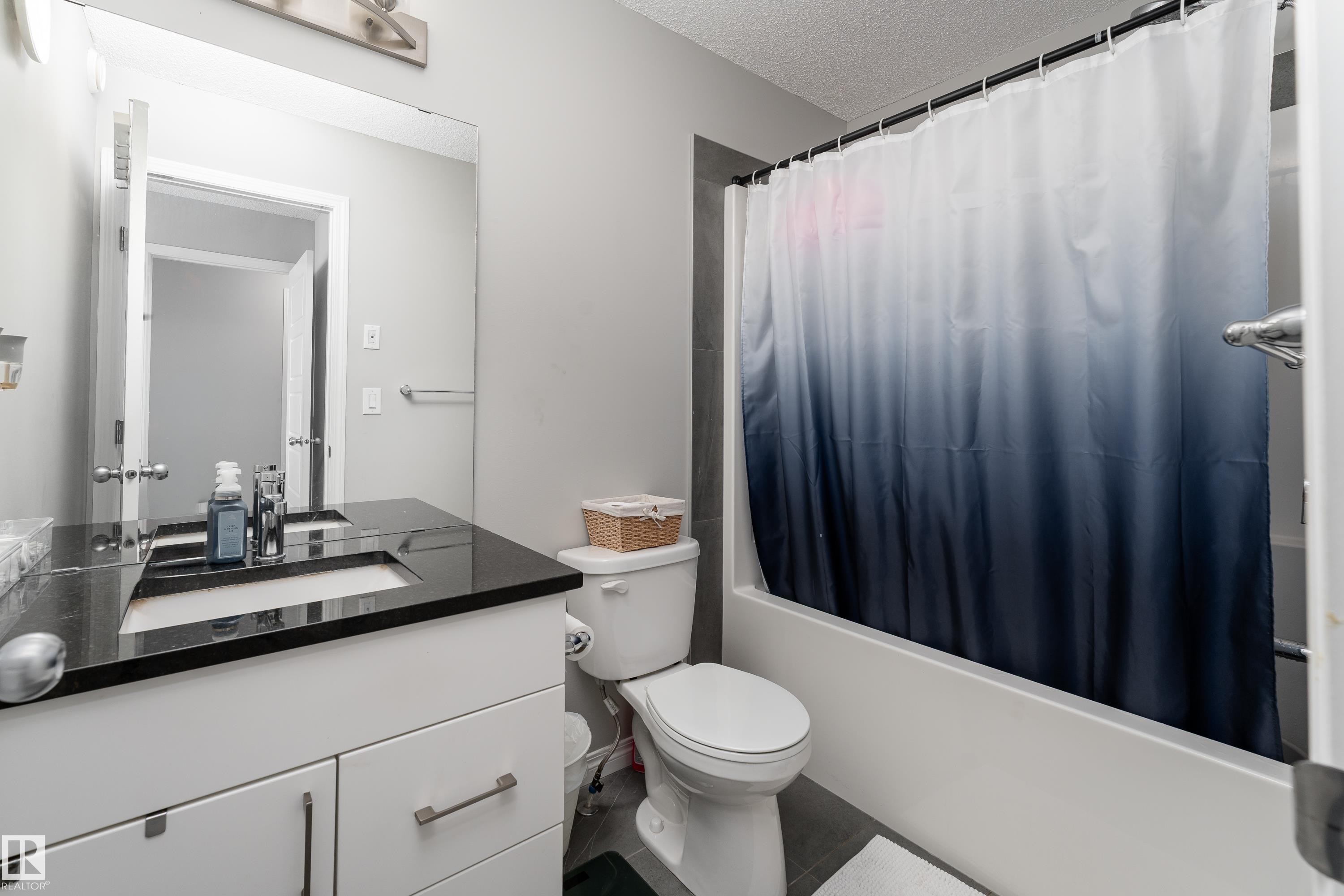 White vanity with a black countertop, undermount sink, and chrome faucet - 20247 16 Avenue Nw, Edmonton, AB