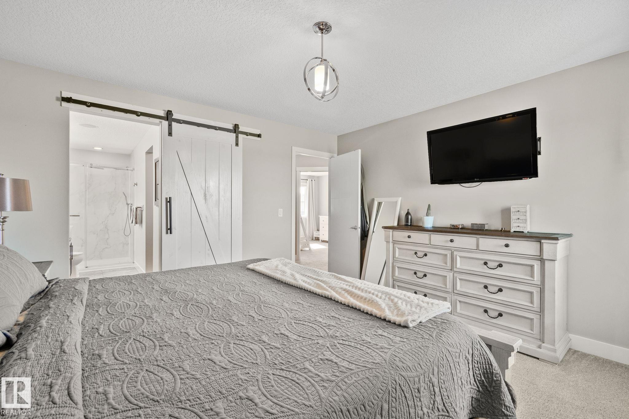Barn door entry to an en-suite bathroom featuring a glass-enclosed shower - 2096 Redtail Common Nw, Edmonton, AB