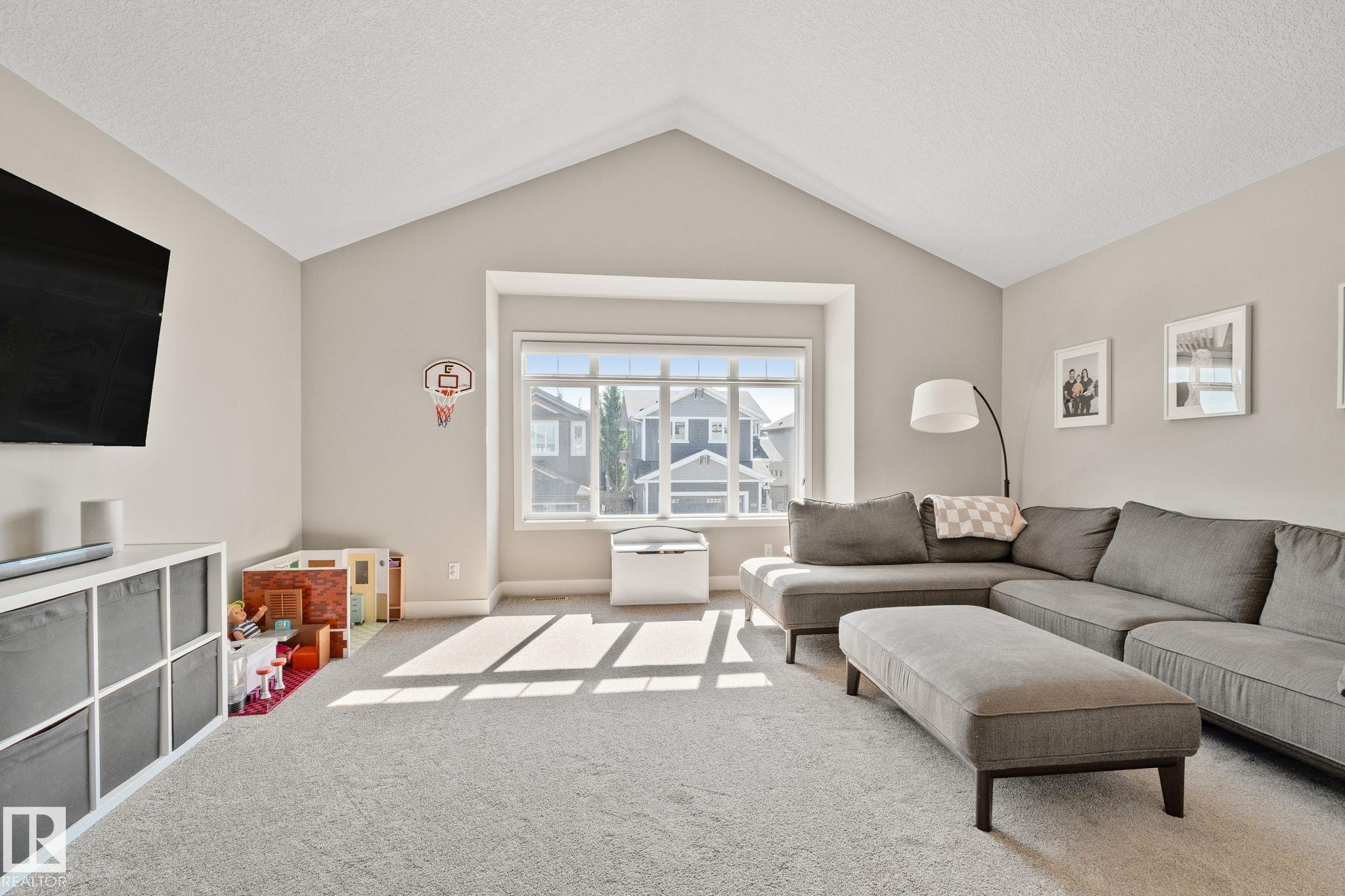 Vaulted ceiling with a large picture window, neutral wall tones, and plush carpet flooring - 2096 Redtail Common Nw, Edmonton, AB