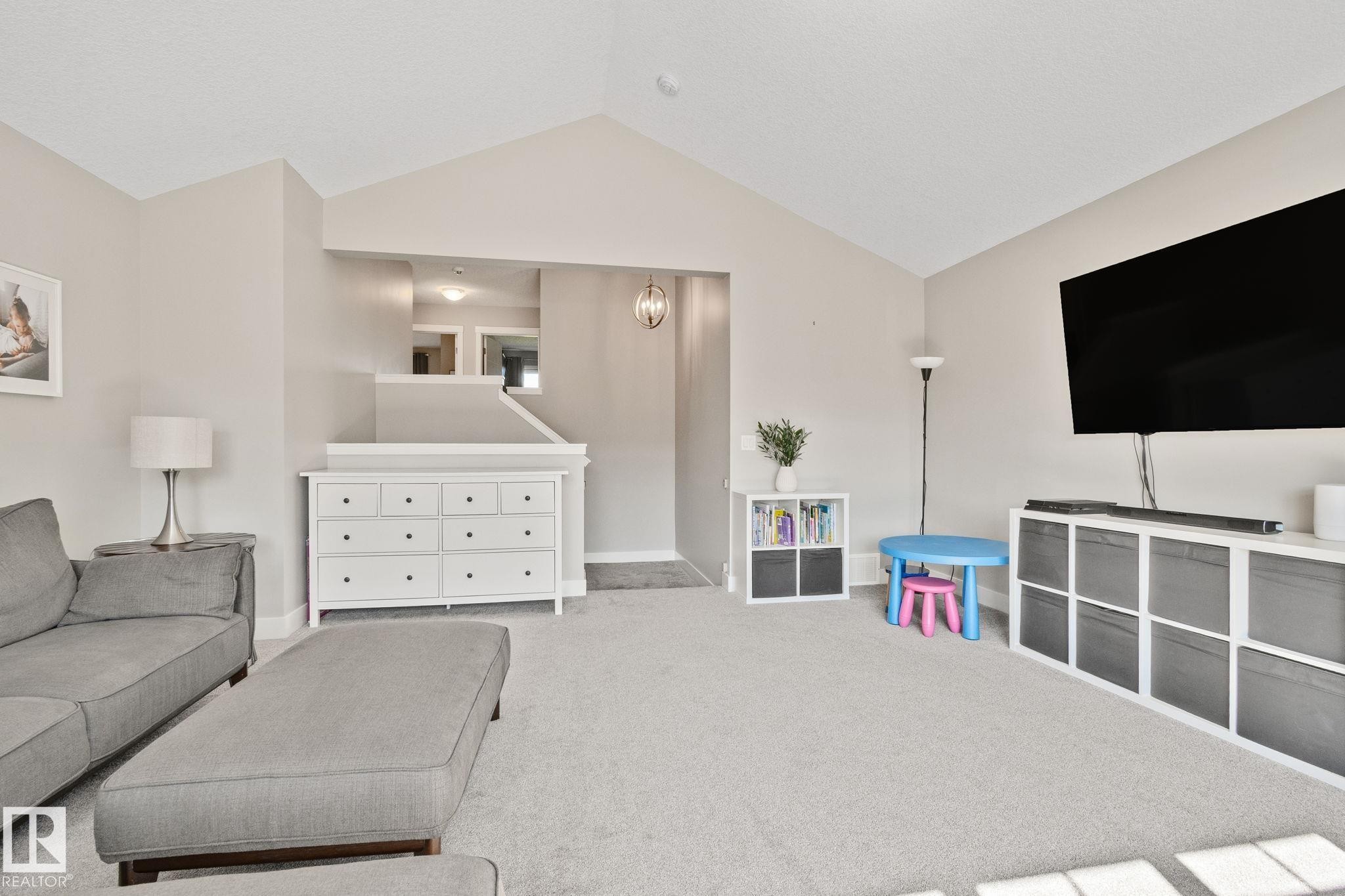 Vaulted ceiling, neutral wall paint, carpeted flooring, upper-level hallway, and a contemporary light fixture - 2096 Redtail Common Nw, Edmonton, AB