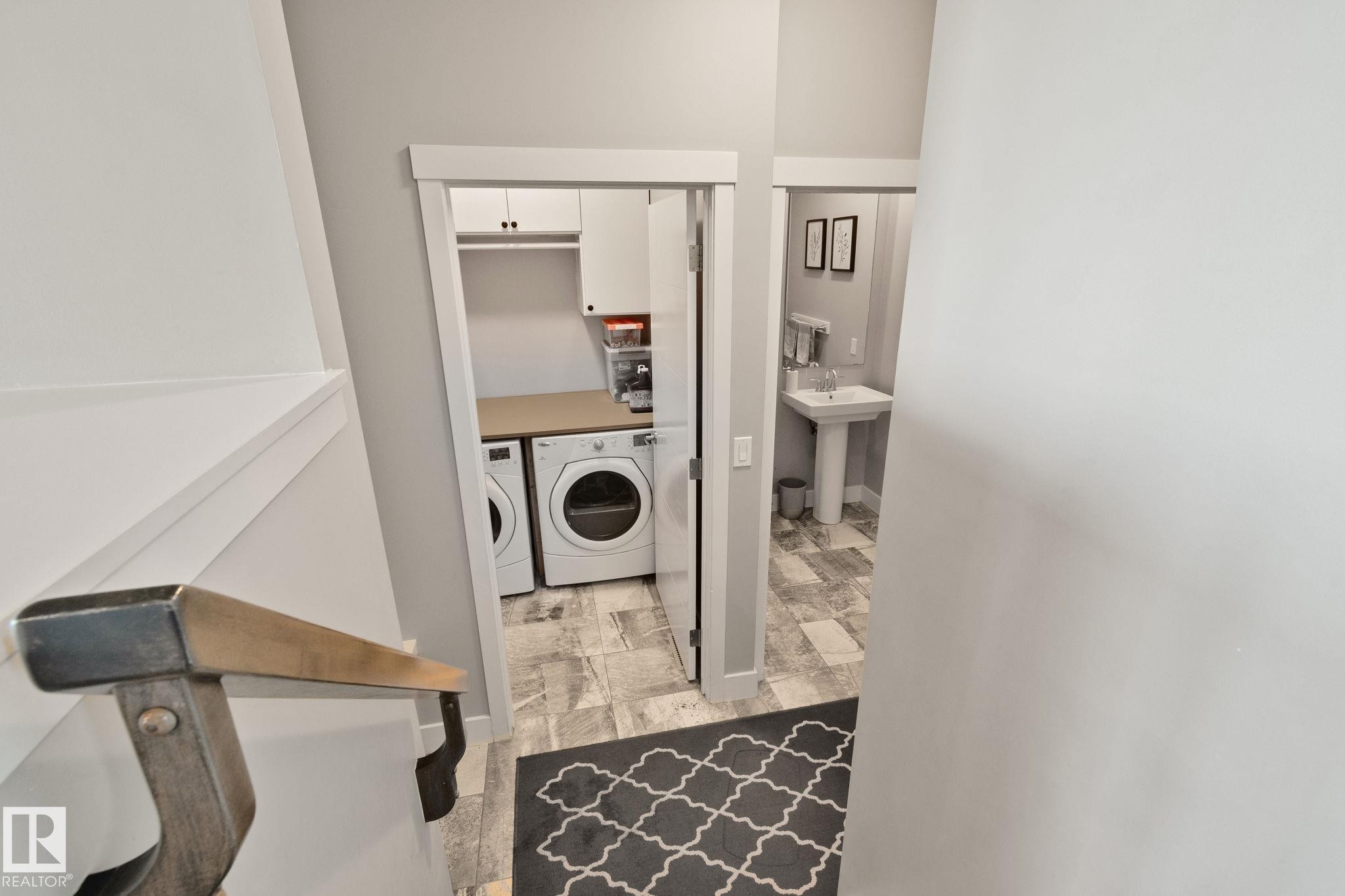 Laundry area with front-load washer and dryer, built-in cabinetry, and countertop - 2096 Redtail Common Nw, Edmonton, AB