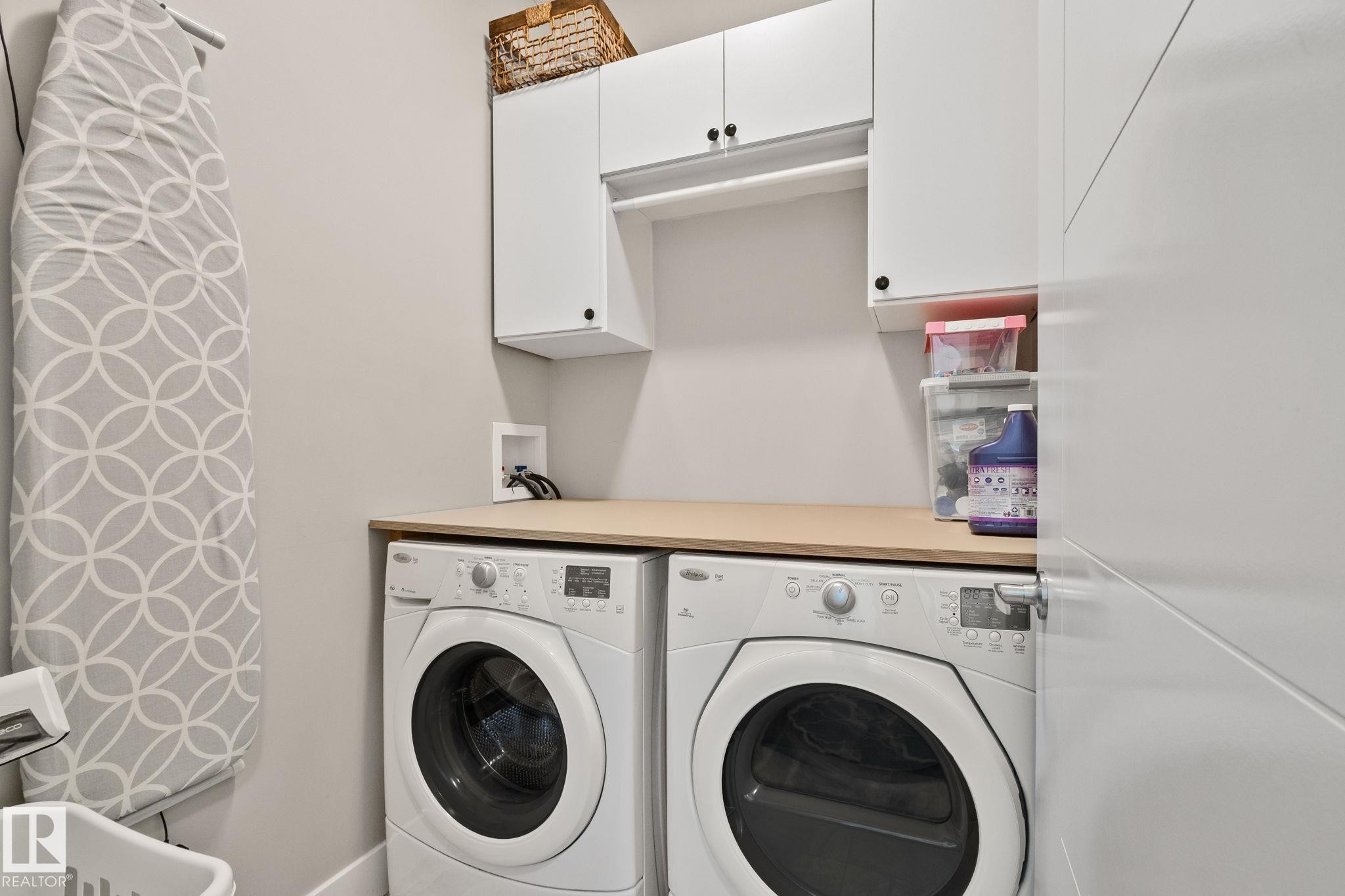 Dedicated laundry space featuring white cabinetry, a light wood-finish countertop, and a built-in hanging rod - 2096 Redtail Common Nw, Edmonton, AB