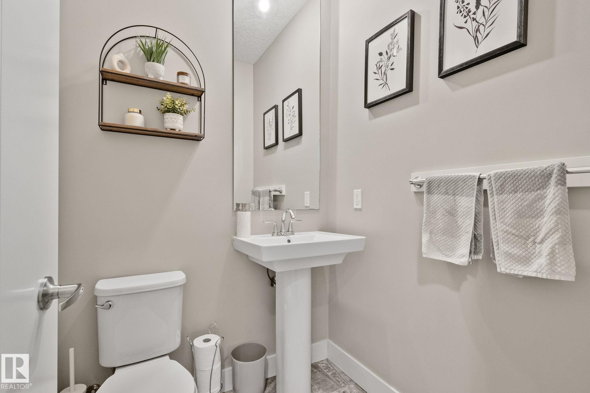 Pedestal sink with chrome faucet, wall-mounted mirror, and tile flooring - 2096 Redtail Common Nw, Edmonton, AB