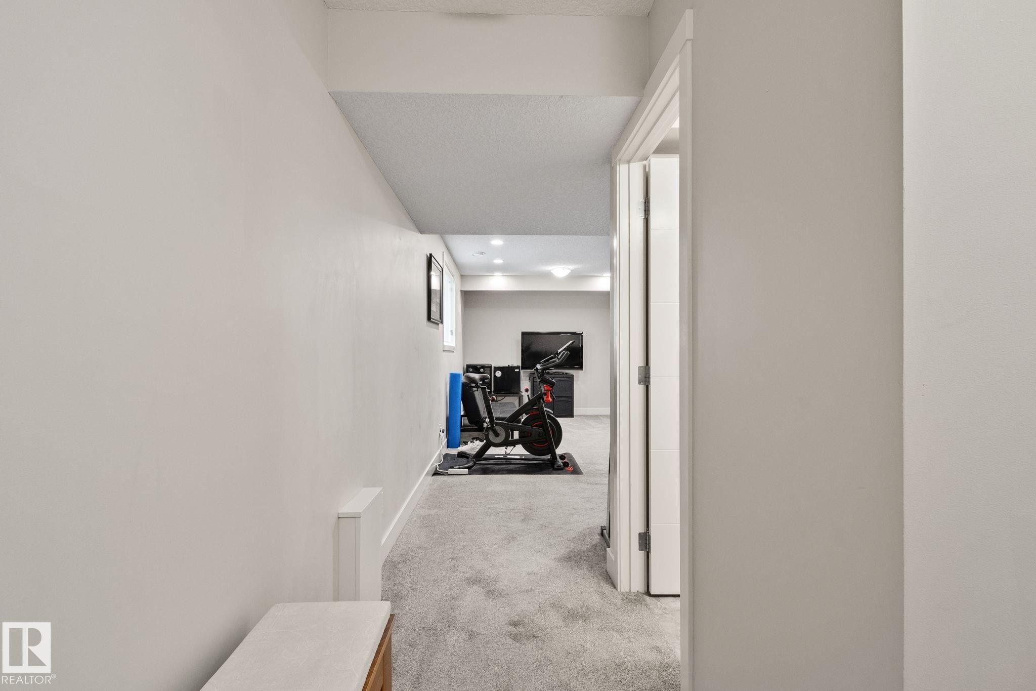 Carpeted hallway with recessed lighting and a white paneled door frame - 2096 Redtail Common Nw, Edmonton, AB