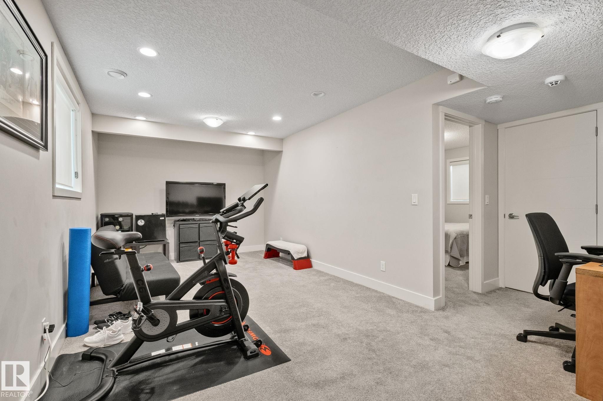 Light gray carpeting throughout a versatile room with recessed lighting and a window - 2096 Redtail Common Nw, Edmonton, AB