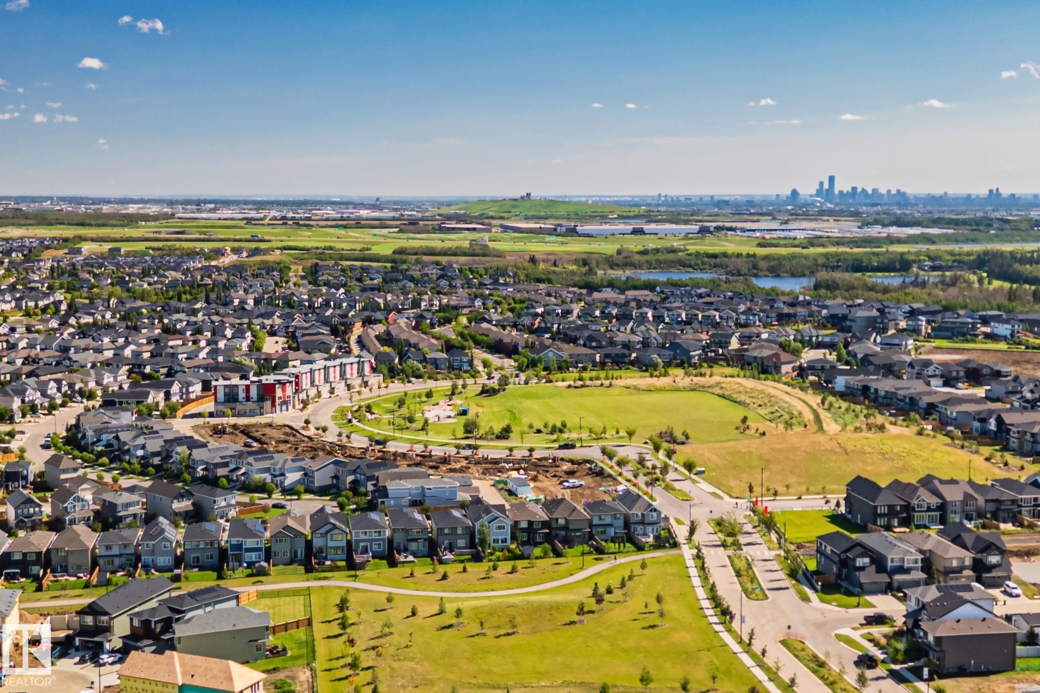 Expansive residential development featuring detached homes, green spaces, and a distant city skyline - 2096 Redtail Common Nw, Edmonton, AB