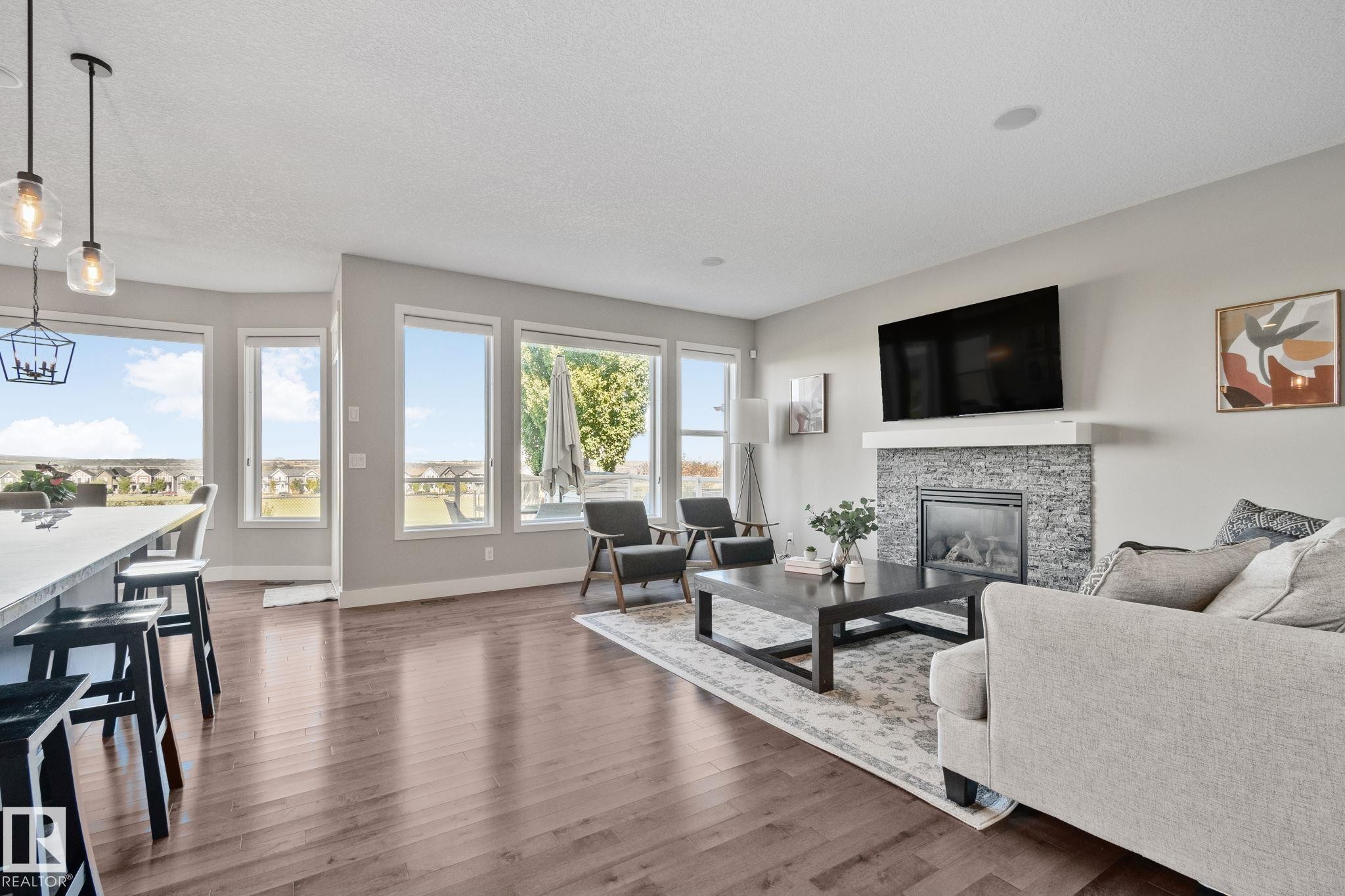 Bright, open-concept living area featuring expansive multi-pane glass doors and windows flooding the space with natural light - 2096 Redtail Common Nw, Edmonton, AB