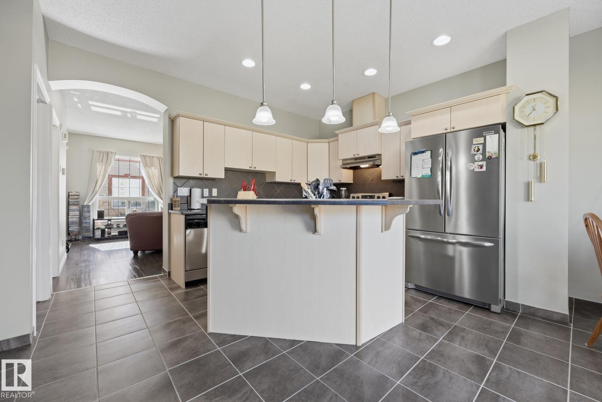 Kitchen featuring a peninsula island, stainless steel appliances, recessed lighting, and tiled flooring - #102 13825 155 Av Nw, Edmonton, AB