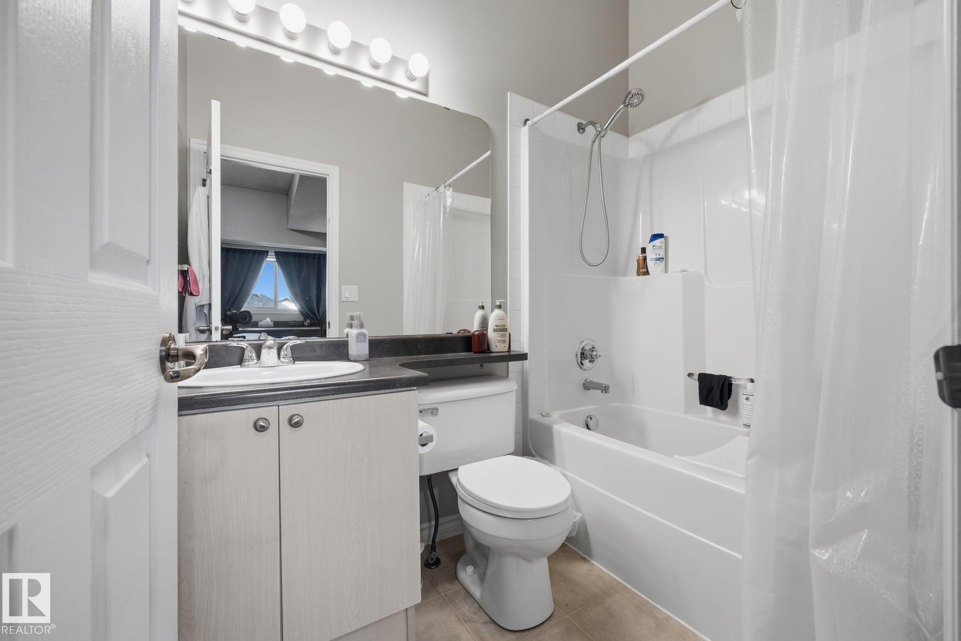 Vanity with integrated sink, dark countertop, and storage cabinetry - #102 13825 155 Av Nw, Edmonton, AB