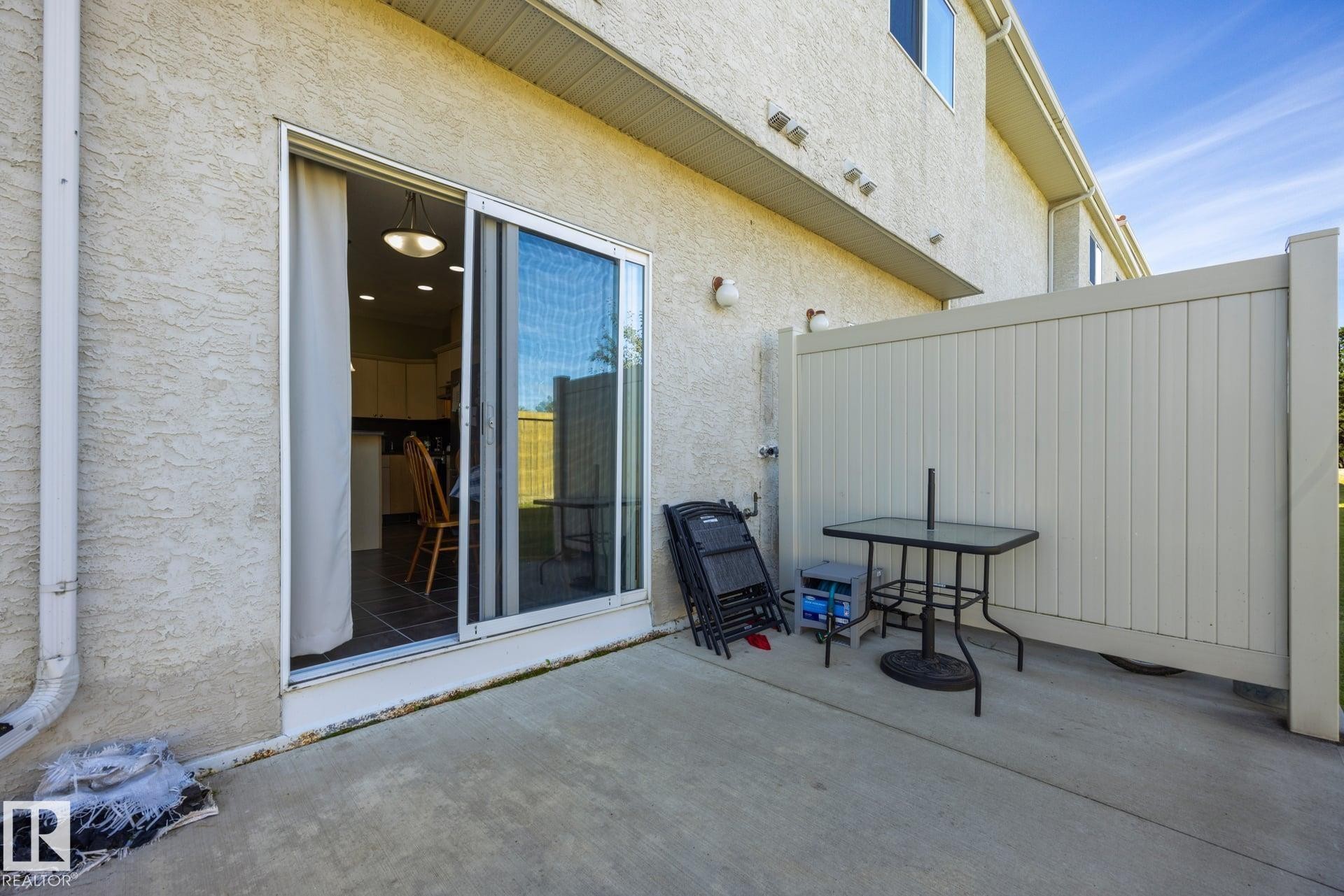 Private patio area featuring a concrete surface and privacy wall - #102 13825 155 Av Nw, Edmonton, AB