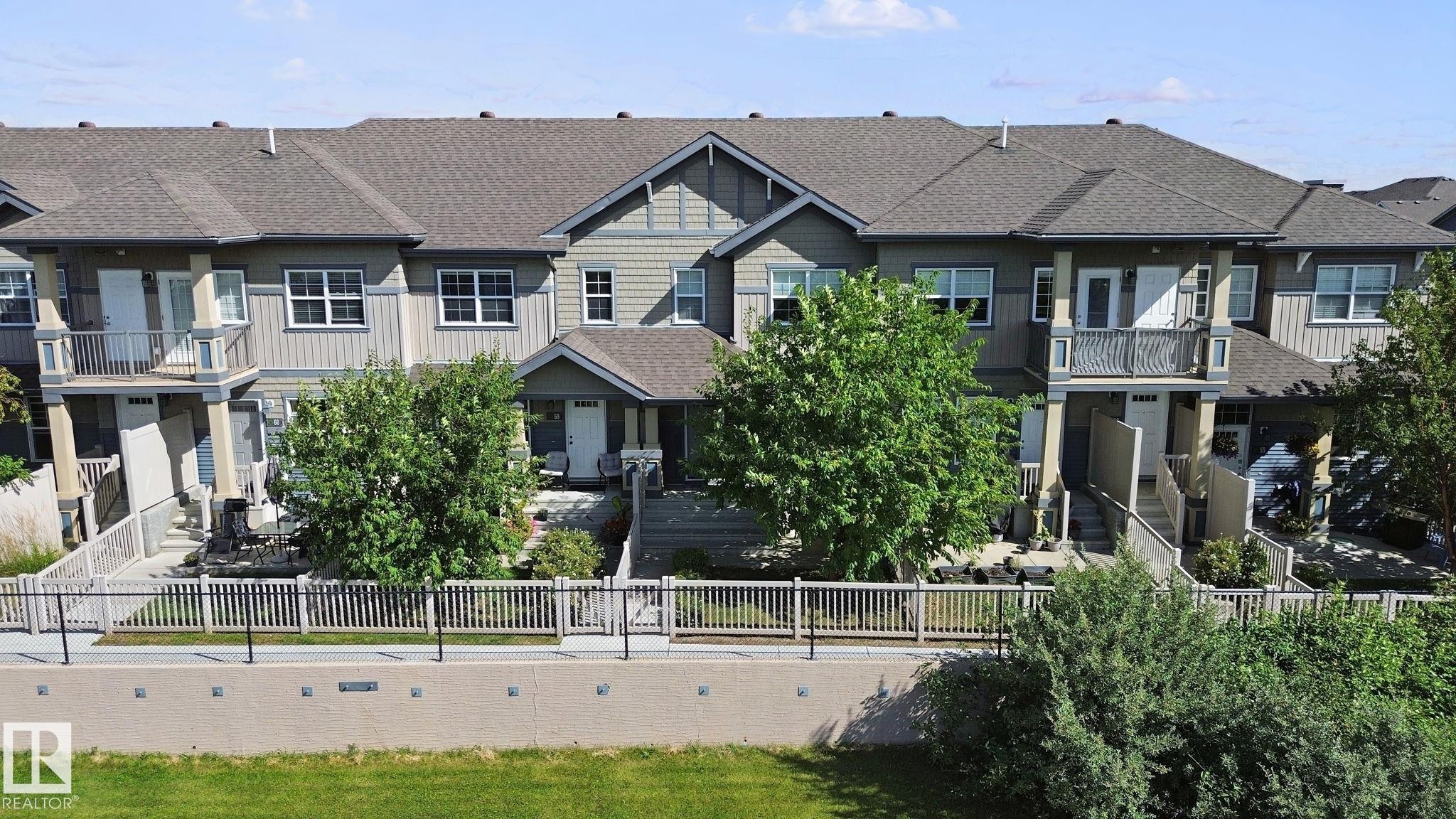Multi-level townhome featuring a neutral exterior, private balconies, and individual fenced patios - #58 4029 Orchards Dr Sw, Edmonton, AB