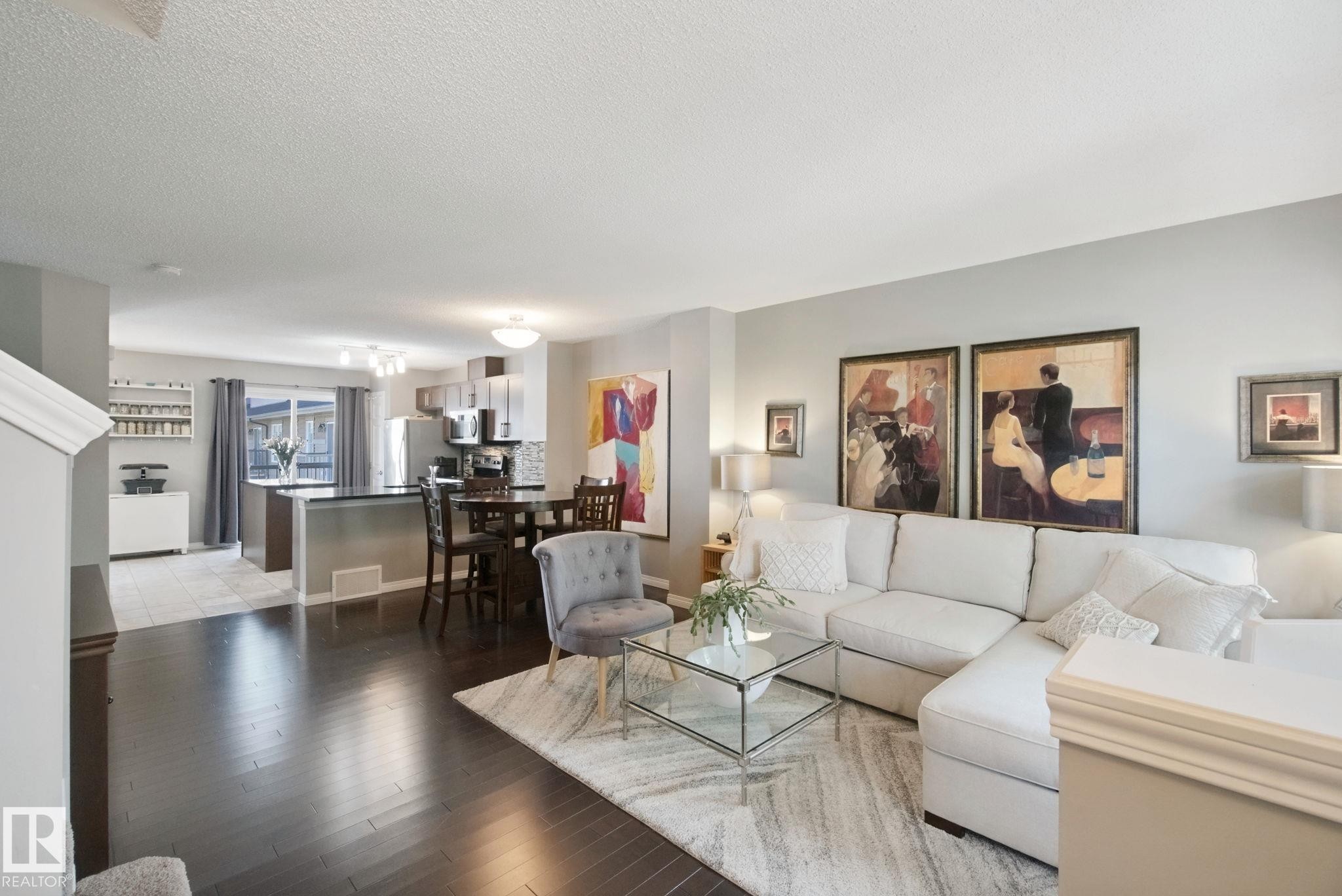 Open-concept living space with dark wood-finish flooring, light grey wall tones, and recessed lighting - #58 4029 Orchards Dr Sw, Edmonton, AB