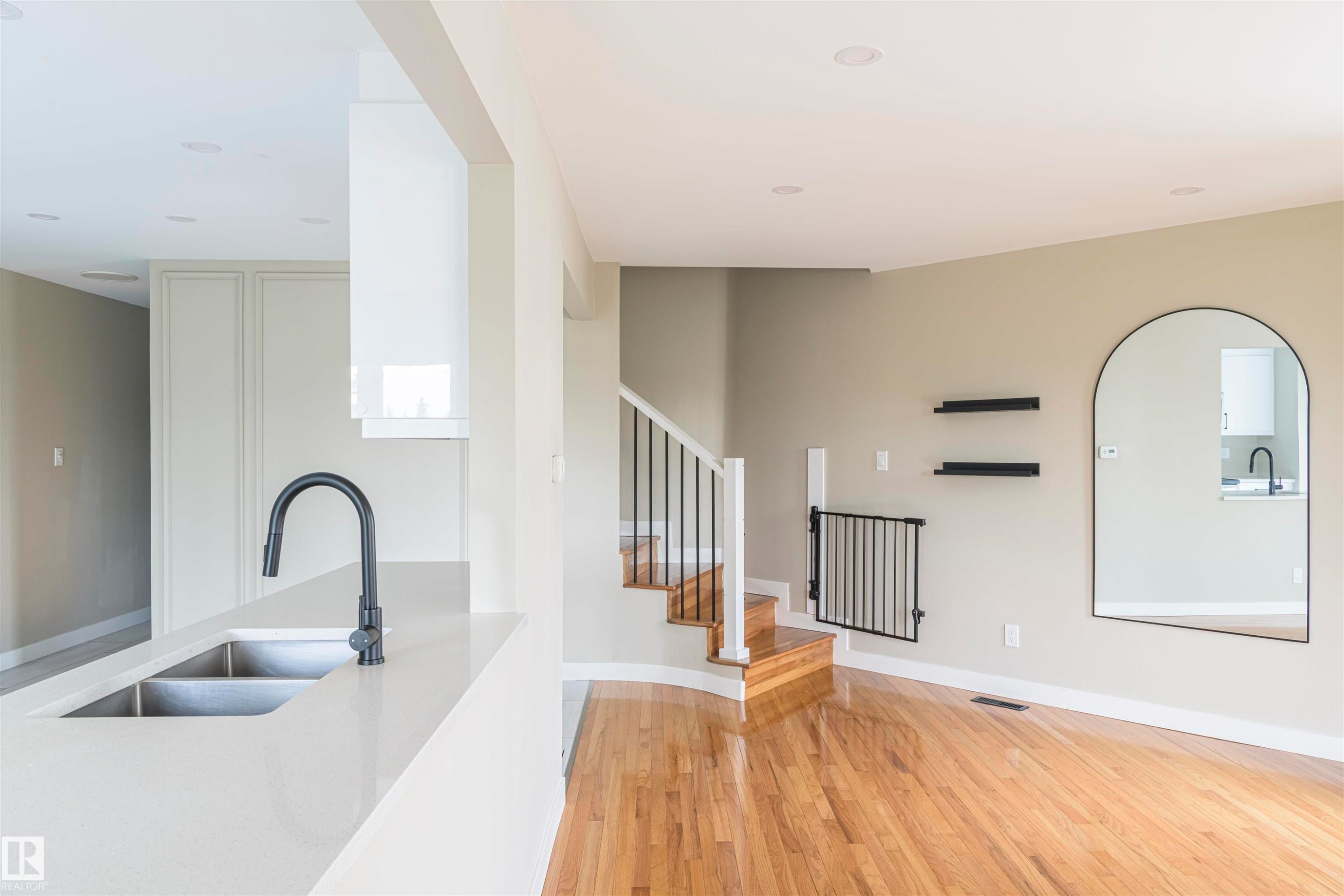 Kitchen island with a double basin stainless steel sink and matte black faucet - 5010 147 Street Nw, Edmonton, AB