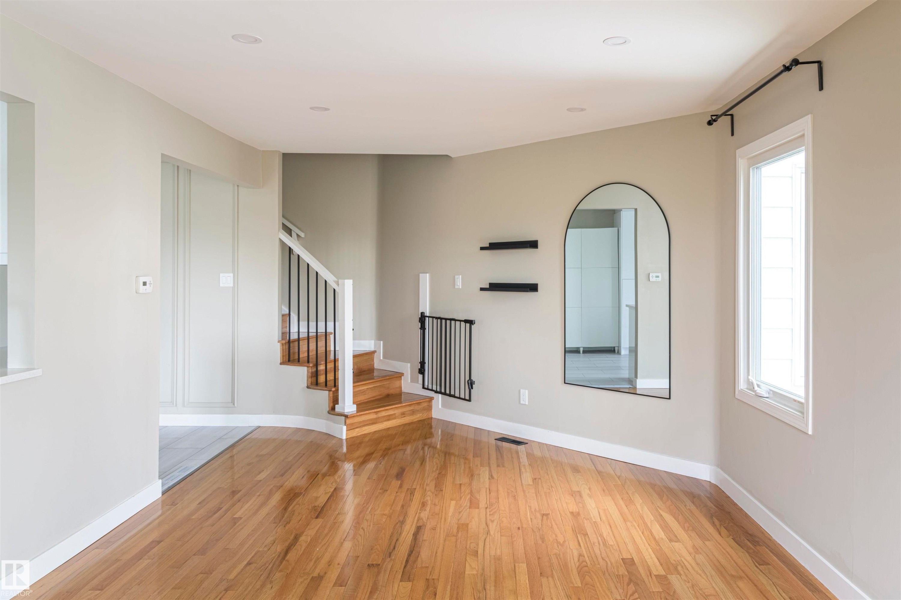 Hardwood flooring with a staircase featuring white risers and railings, black balusters, and wood treads - 5010 147 Street Nw, Edmonton, AB