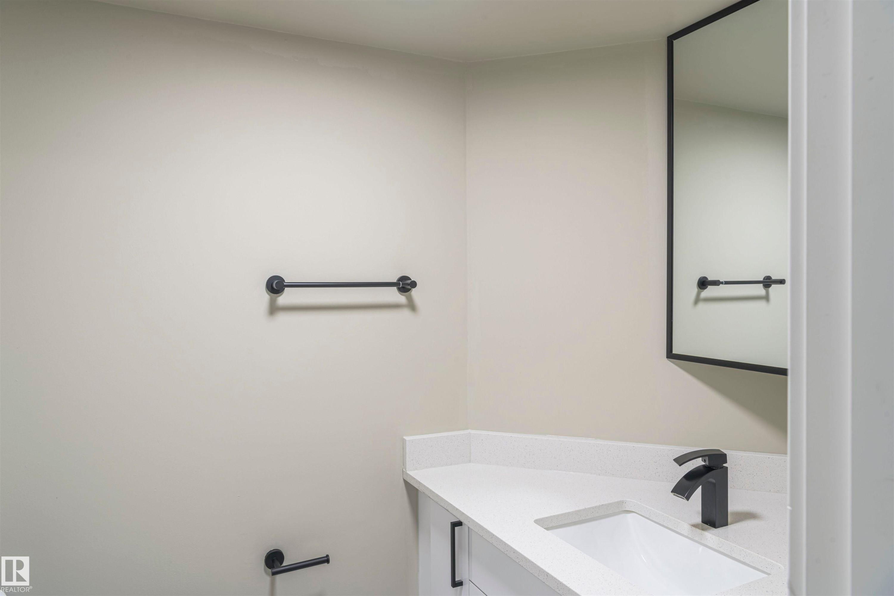 Contemporary vanity with a white countertop and integrated sink, complemented by a matte black faucet - 5010 147 Street Nw, Edmonton, AB