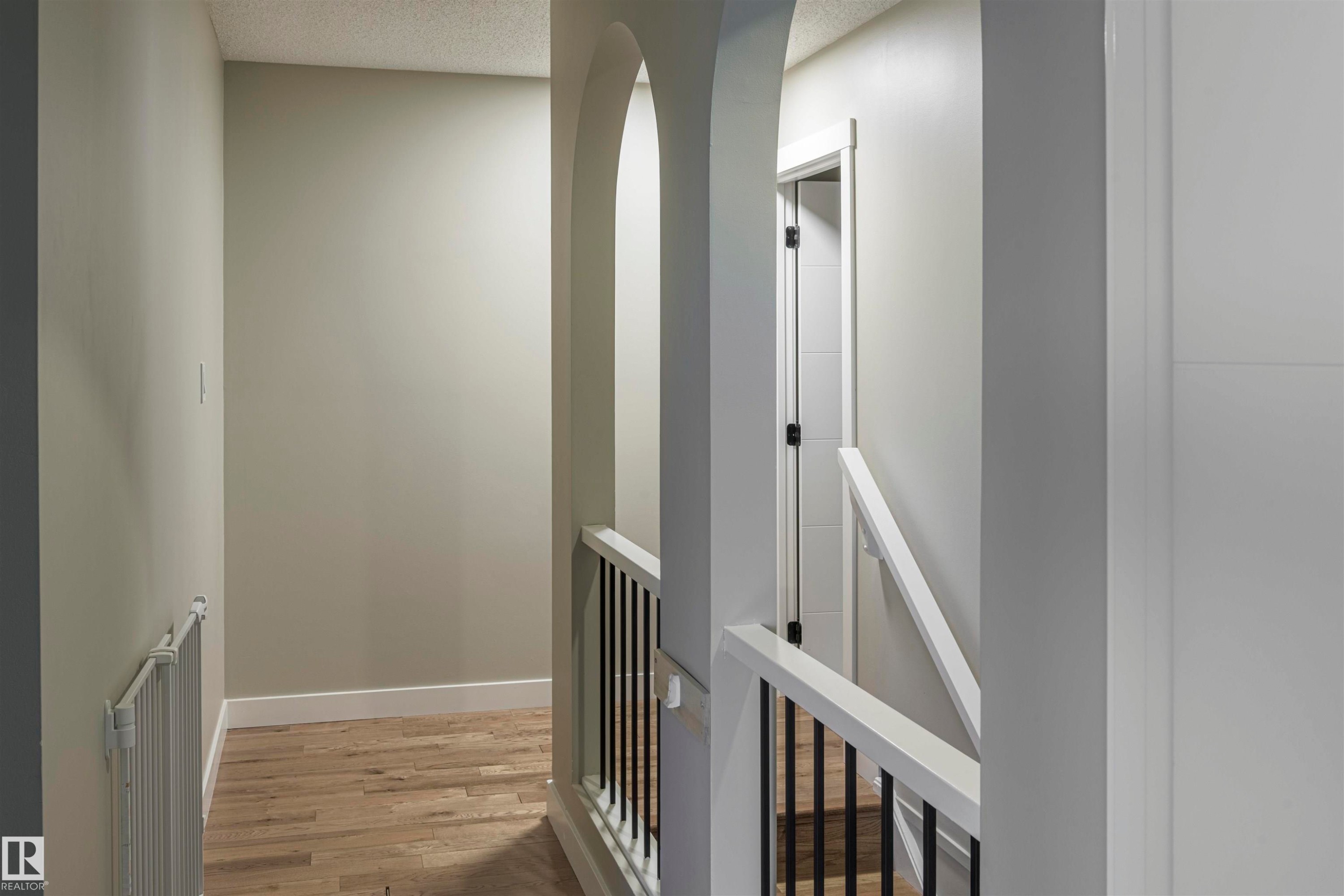 Hallway featuring light-toned wood-finish flooring, white baseboards, and neutral wall paint - 5010 147 Street Nw, Edmonton, AB