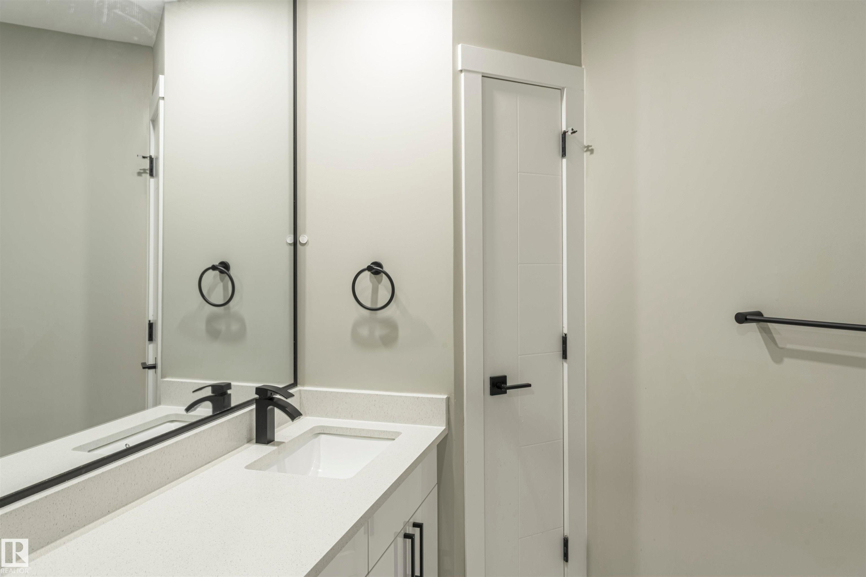 Contemporary bathroom vanity featuring a rectangular undermount sink, light-toned countertop, and matte black faucet - 5010 147 Street Nw, Edmonton, AB